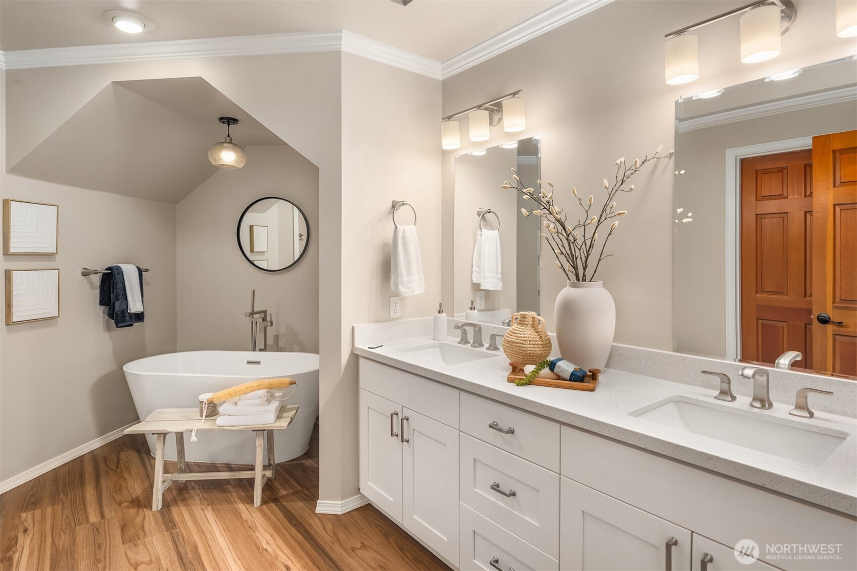 Newly remodeled primary bathroom with white cabinets, quartz countertops, crown moulding, and freestanding tub.