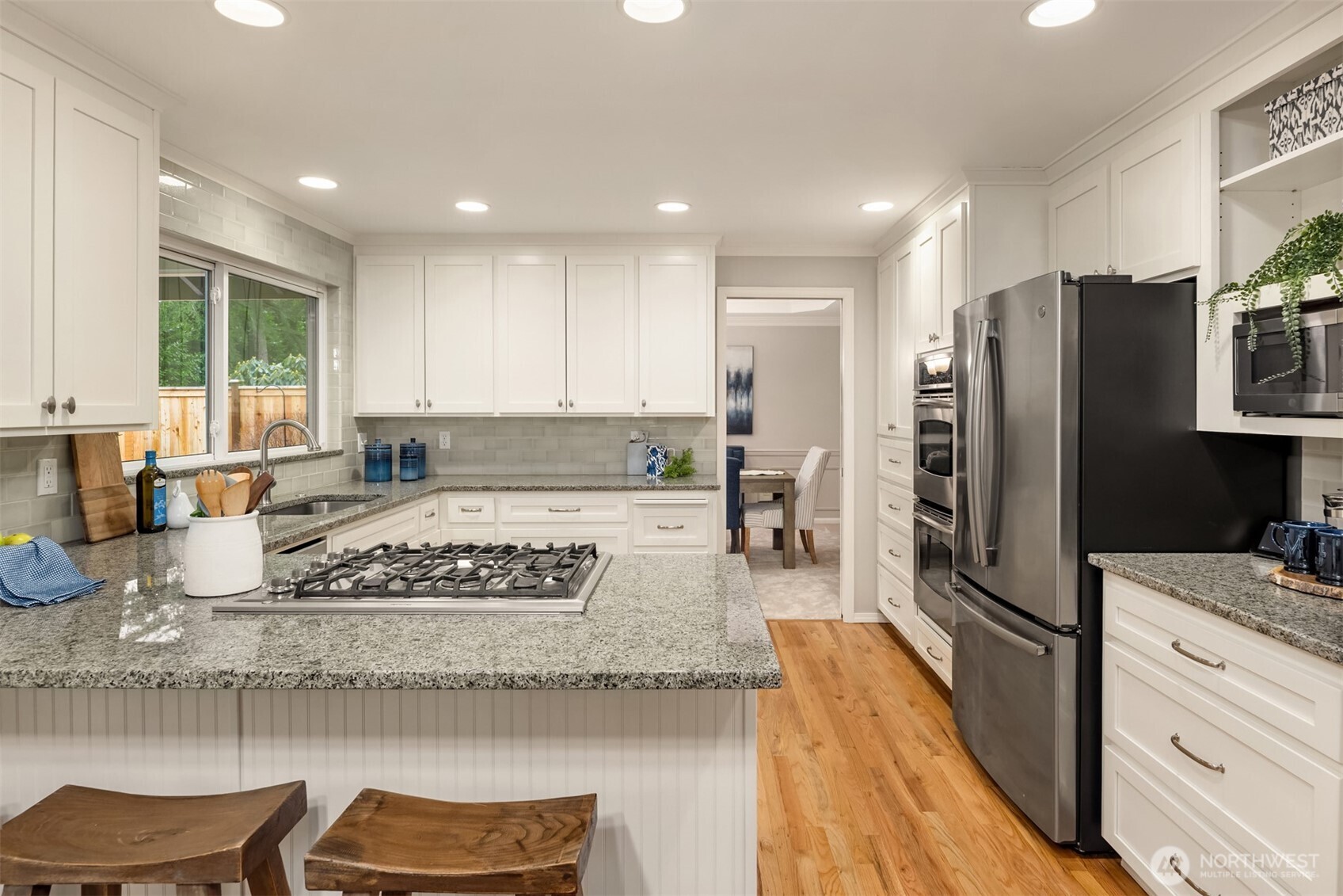 This chef's kitchen features white cabinets, undercounter lights, 4 burner Viking gas cooktop, double oven, french door refrigerator and granite countertops