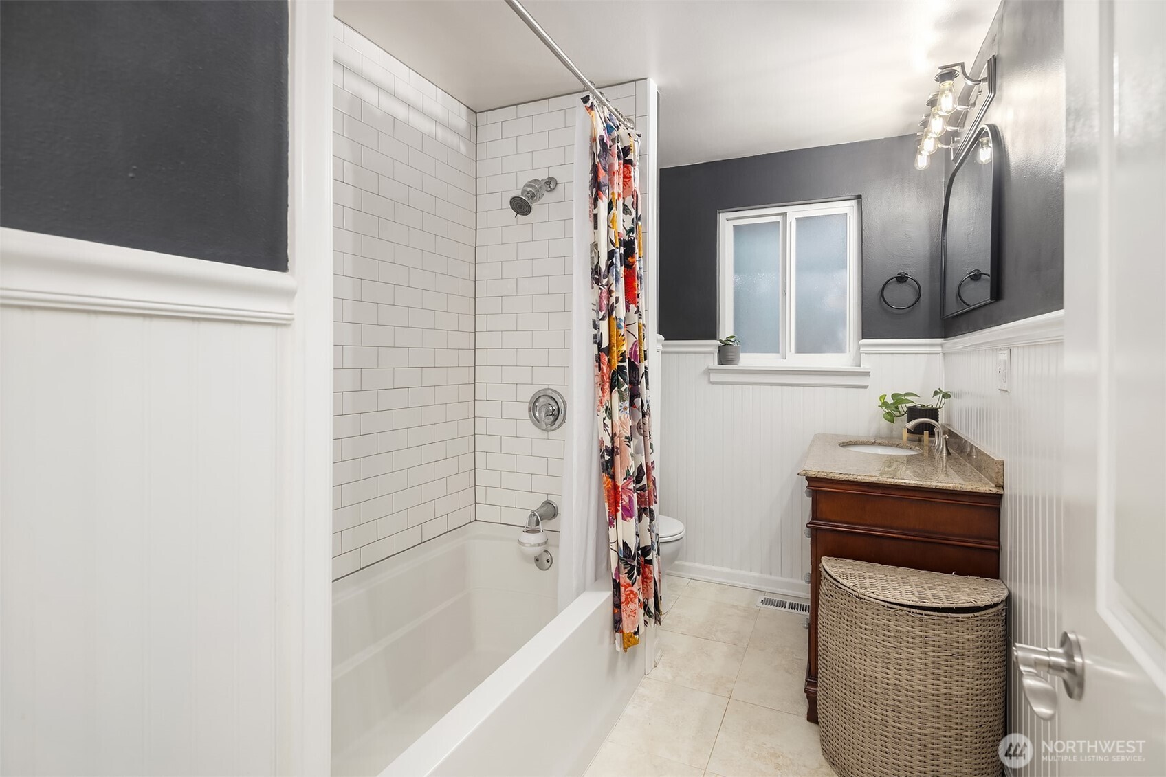 Updated bathroom featuring sleek tub with subway tile and a spacious vanity.