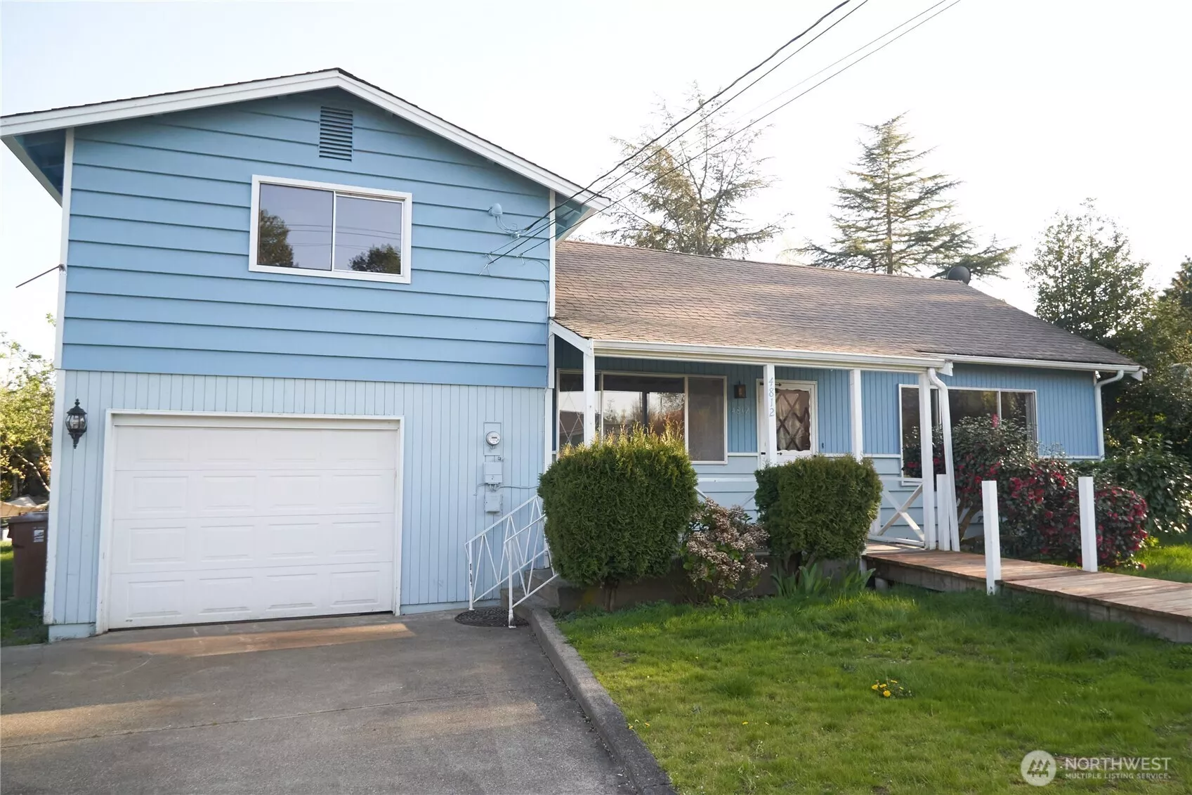 Front of home with a ramp and short set of stairs on side by garage.