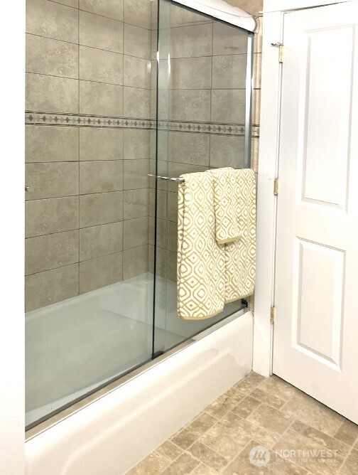 Classic tile design surrounding the tub and glass shower doors.