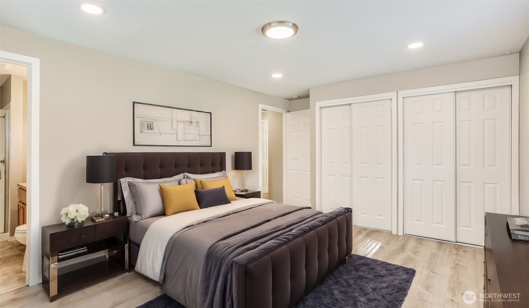 Spacious primary bedroom with two closets and 3/4 bath en suite, virtually staged to show option for residential living.