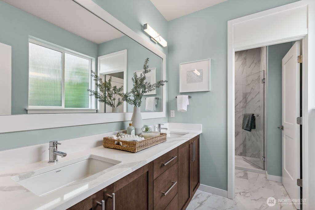Primary bathroom with slab quartz countertops, double sinks, and separate shower and toilet room.