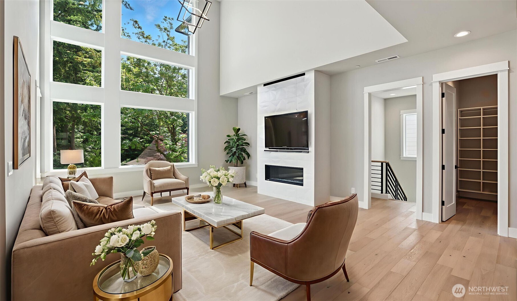 Awe-inspiring Great Room with its mesmerizing 20' ceiling, and sleek modern fireplace framed by breathtaking custom tile work! Virtually staged. Door to the immediate right of the fireplace leads to the Guest Suite and staircase down to the spacious Rec Room.
