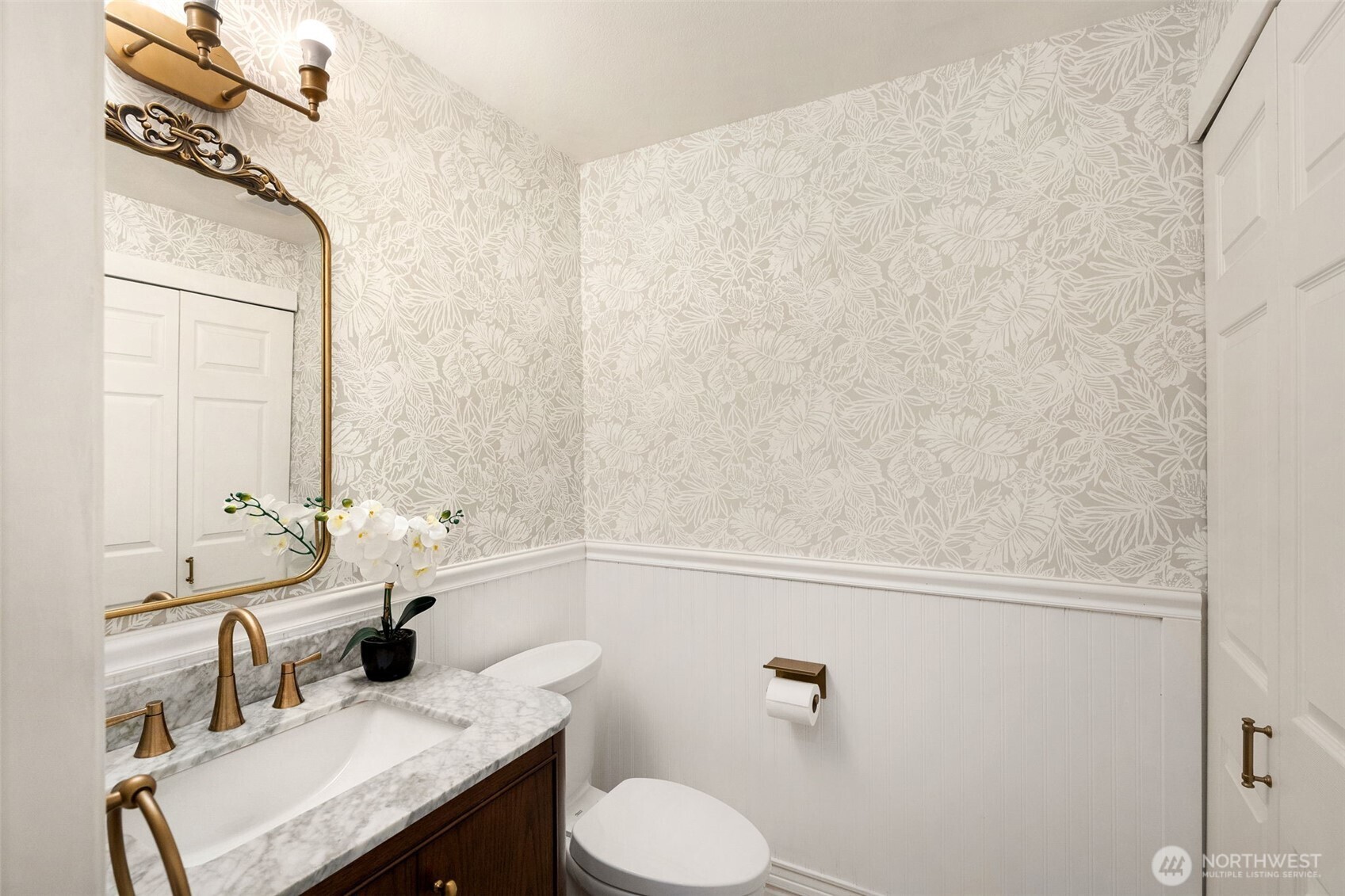 Main floor bathroom with wainscotting and fun wallpaper
