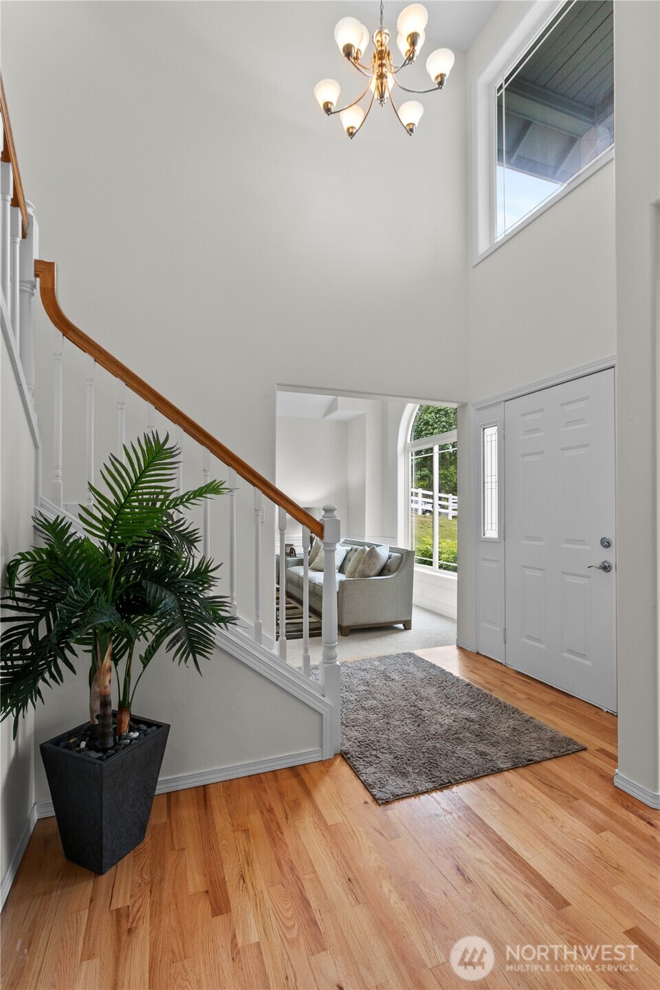 Foyer with vaulted ceiling. Living room in background. Behind and to the right is the laundry/mud room and the office/den.