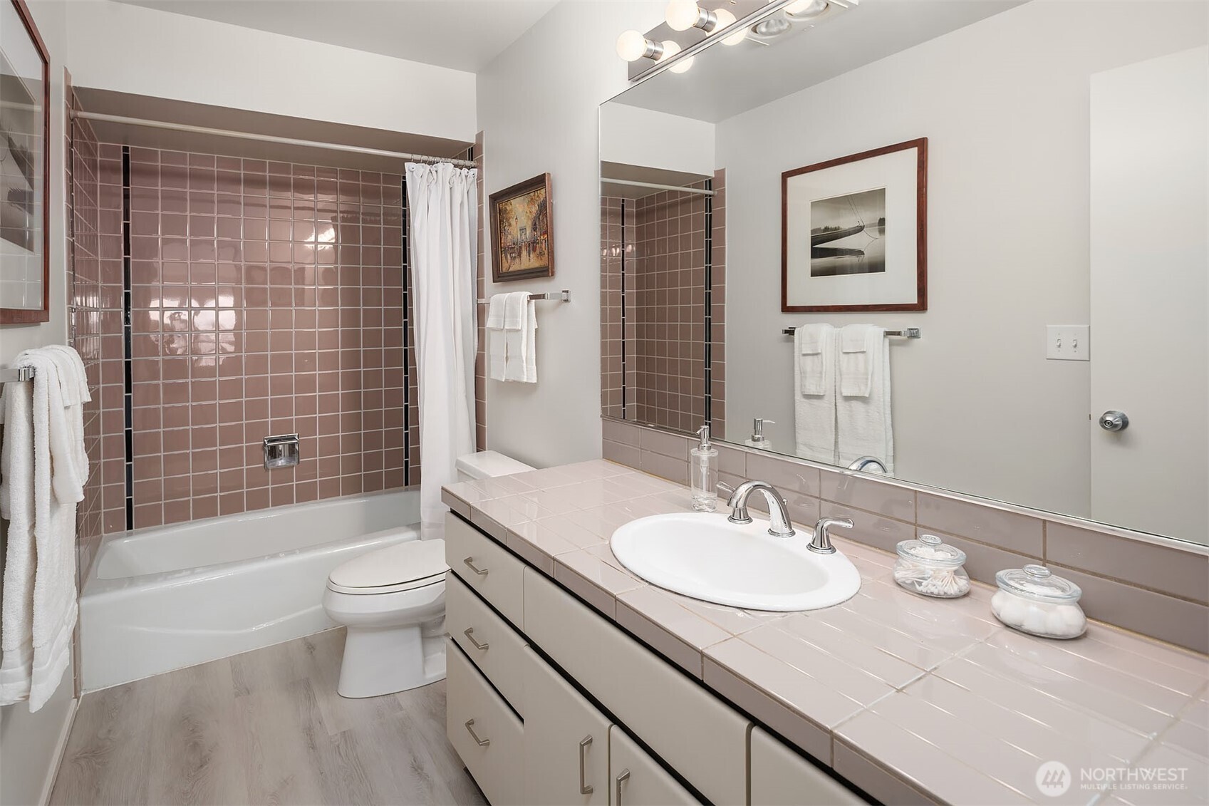 Upstairs guest bath featuring a full tile tub and shower, complemented by luxurious vinyl plank flooring and an expansive vanity.