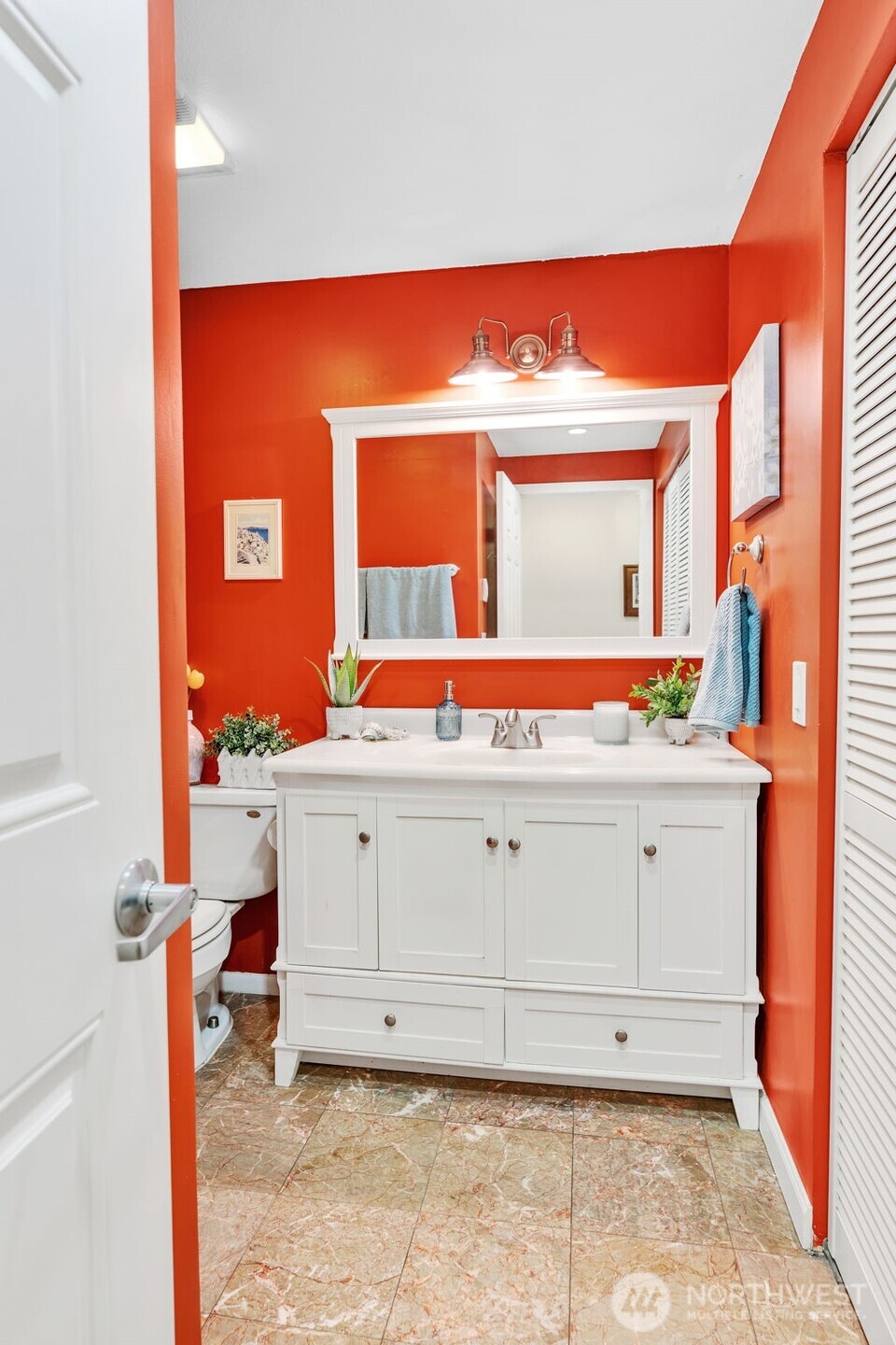 The bathroom features heated marble flooring and beautifully updated vanity, mirror, and light fixture. The laundry is to the right of this photo.