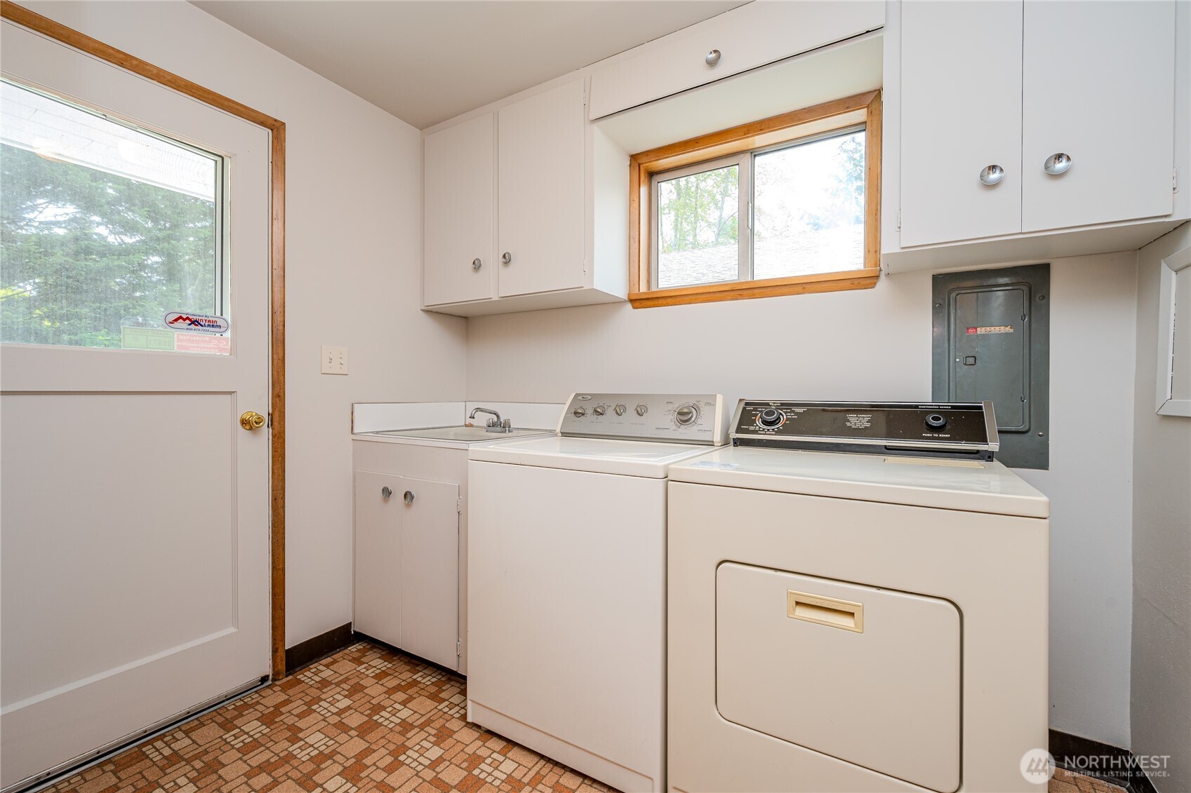 The Laundry Room features a utility sink, washer & dryer, plenty of storage in cabinetry & a spacious pantry to the rear in this photo.