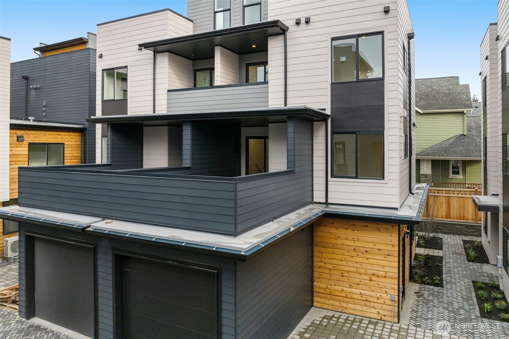 The back exterior shows off the layered design with wood accents, a balcony, and an attached garage.