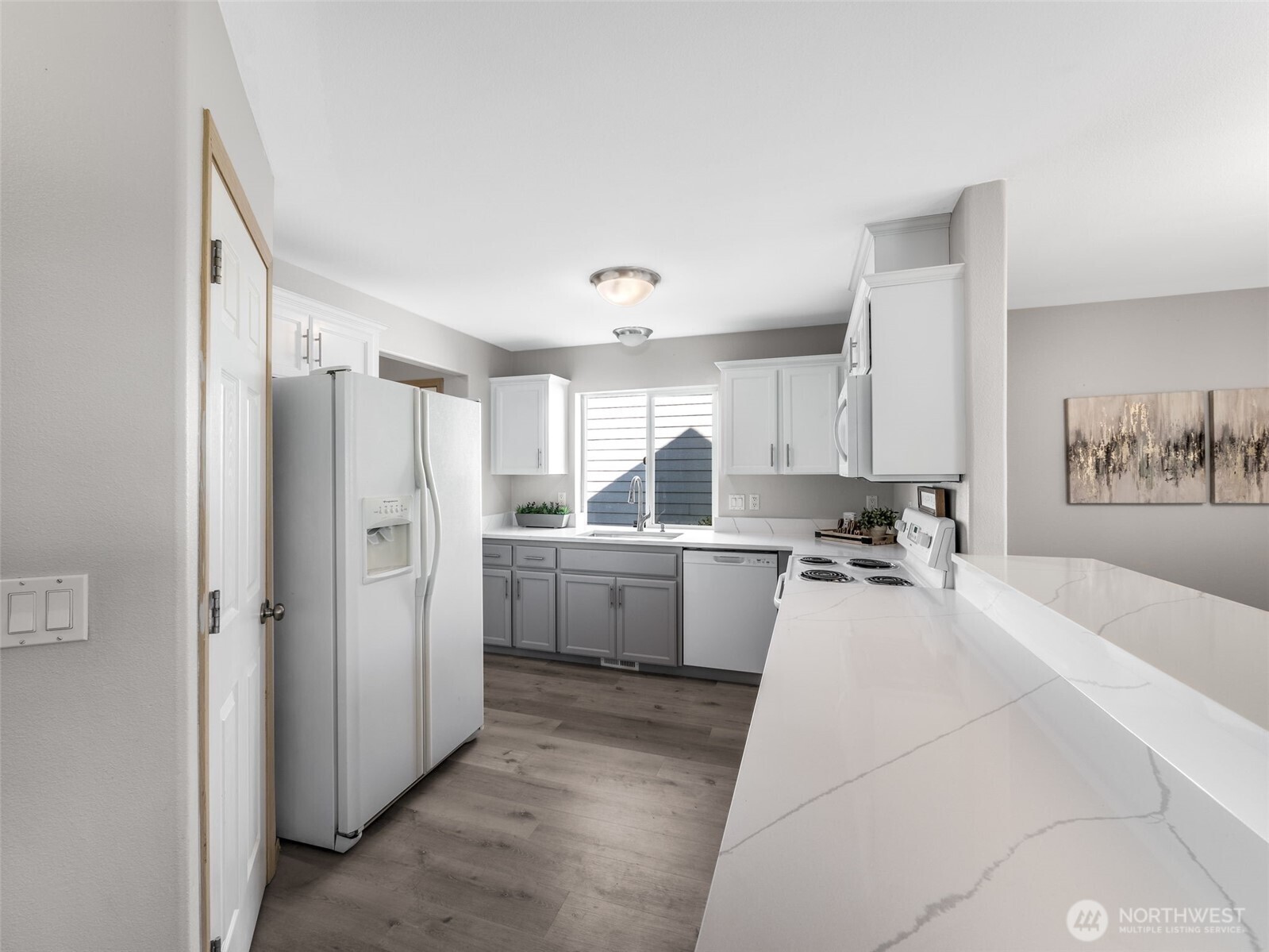 Kitchen view from the other side showing the gorgeous quartz countertops and the breakfast bar! So much counterspace for meal prep, making cookies, and don't forget homework time on the breakfast bar.