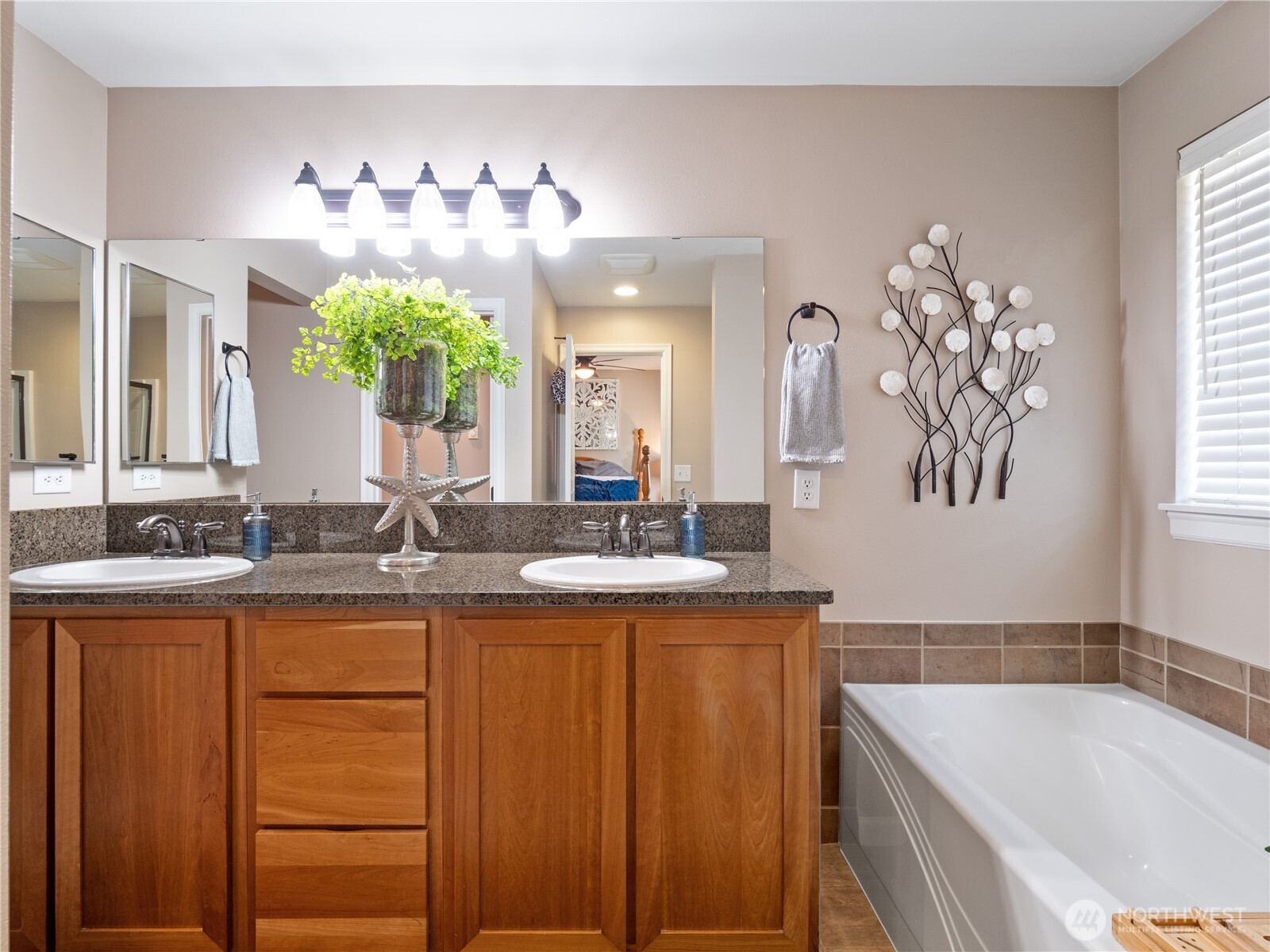 Spacious primary bathroom featuring a double vanity with ample counter space and warm wood cabinetry, alongside a relaxing soaking tub.