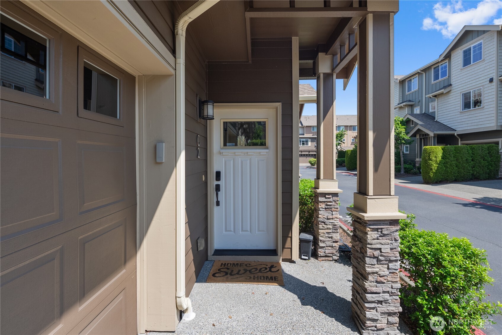 Step into comfort and charm—this inviting covered entryway welcomes you home with craftsman-style columns, stacked stone details, and a cheerful "Home Sweet Home" greeting.