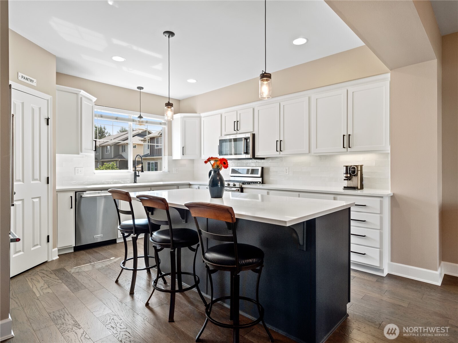 Featuring crisp white cabinetry, sleek quartz countertops, and a stunning dark island with bar seating, the space is ideal for both casual dining and entertaining.