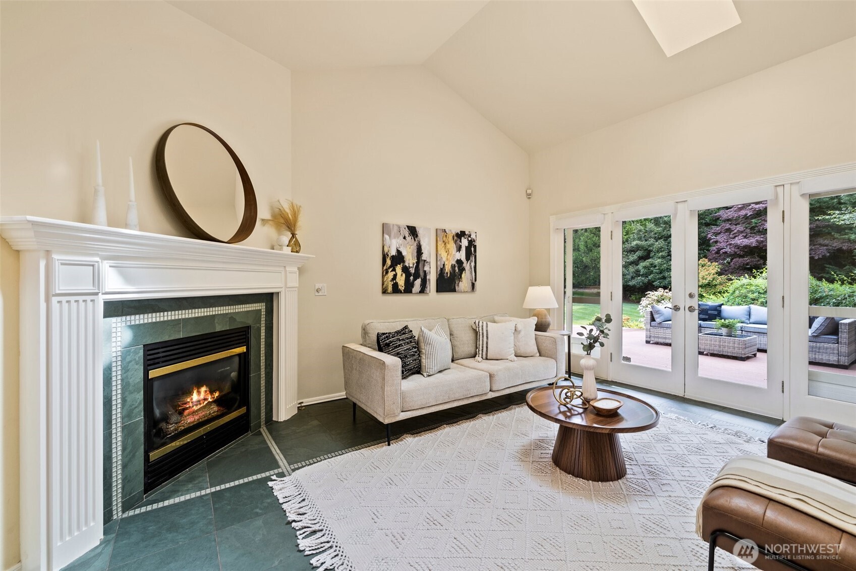 Family room off the kitchen with slate floors, gas fireplace, vaulted ceilings, skylight and French doors open to the backyard deck and large level backyard.