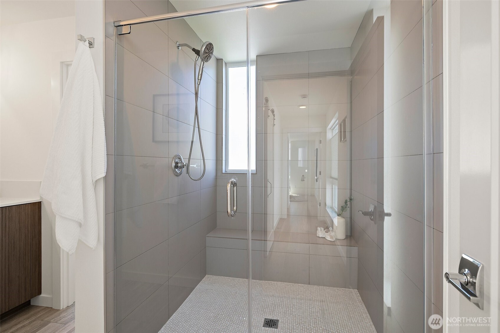 Primary suite bathroom with frameless shower door, tile bench and timeless style.