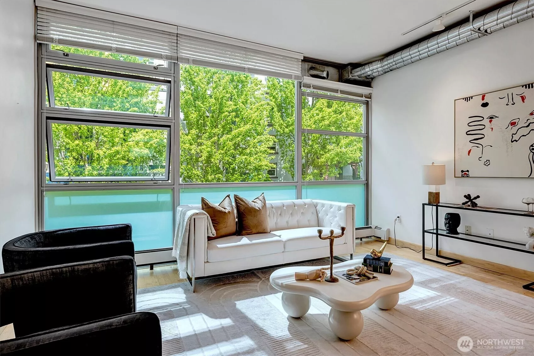 Floor-to-ceiling steel windows frame lush, park-like setting