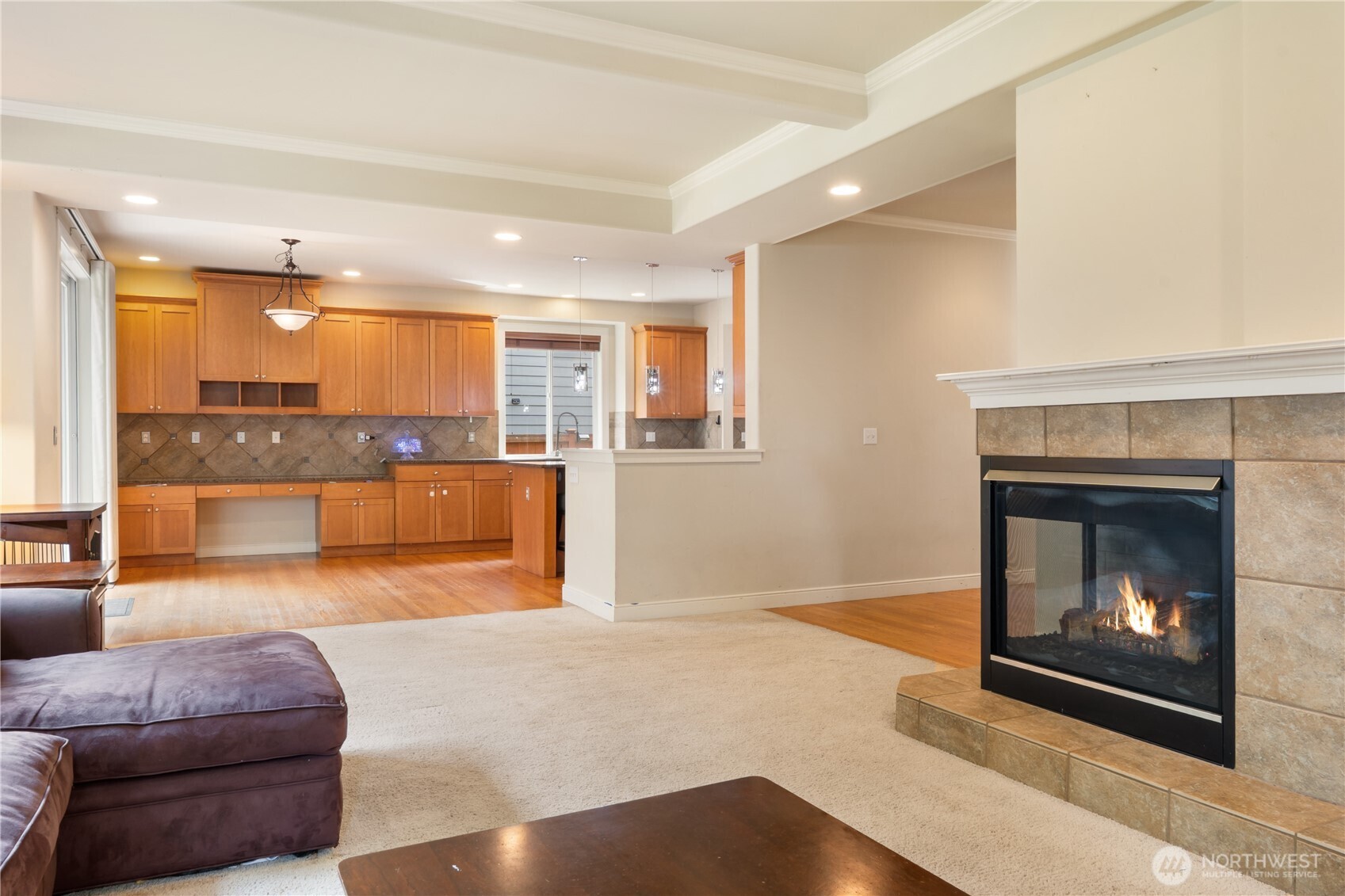 Gather around the double-sided gas fireplace in this inviting living space with large windows and backyard views.