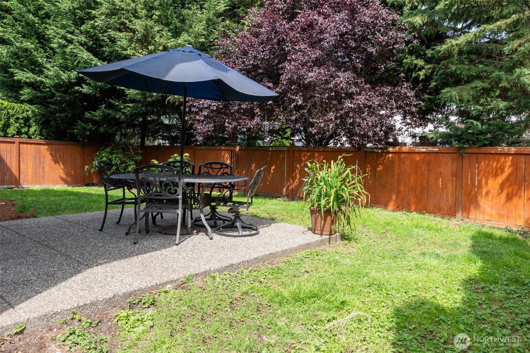 Enjoy alfresco dining on the private patio surrounded by privacy fencing and vibrant foliage.