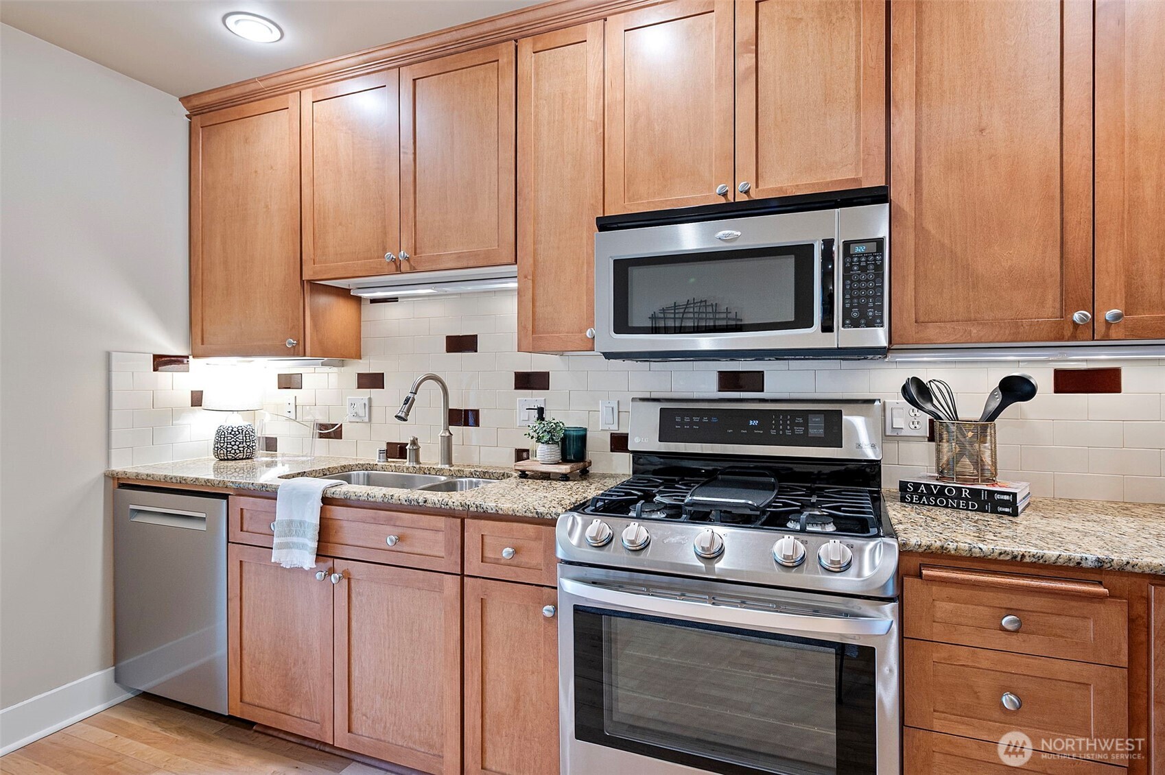 Stainless appliances, under counter lighting, granite counters with oak floors