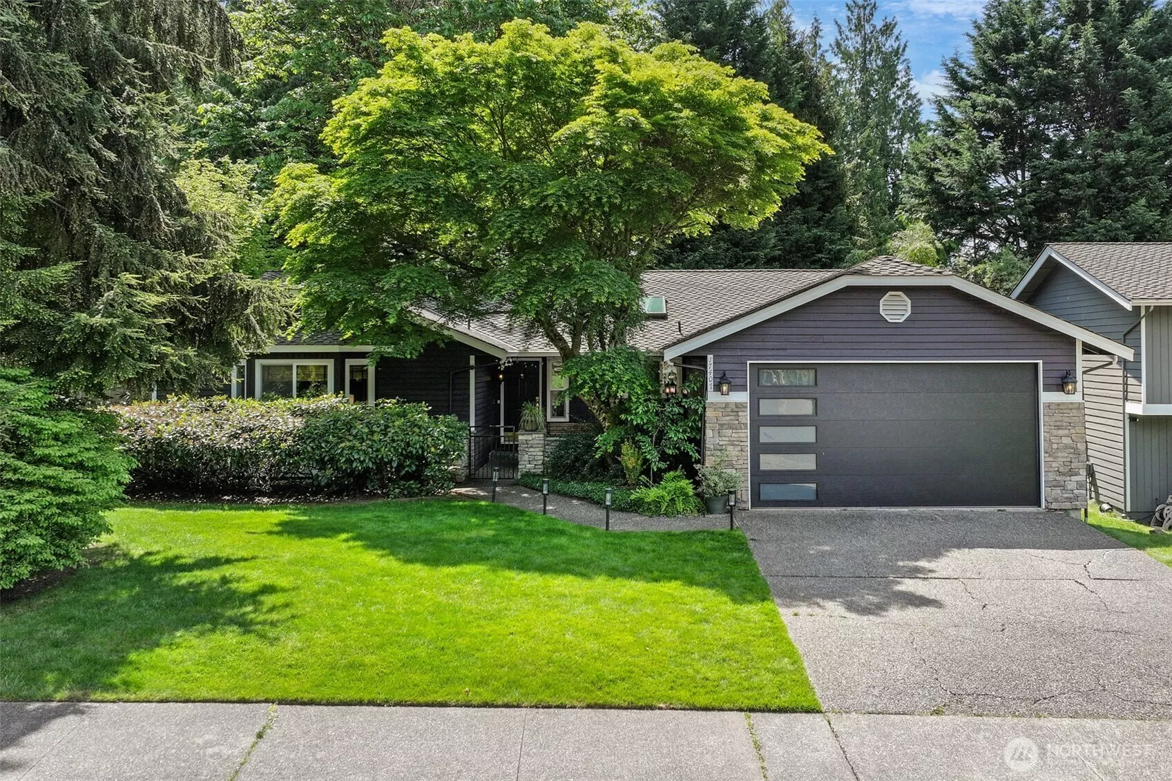 Nestled beneath mature trees, this charming rambler offers exceptional curb appeal with a blend of contemporary and natural design. The modern garage door, stone accents, and manicured landscaping welcome you home to this peaceful English Hill setting within the sought-after Northshore School District.
