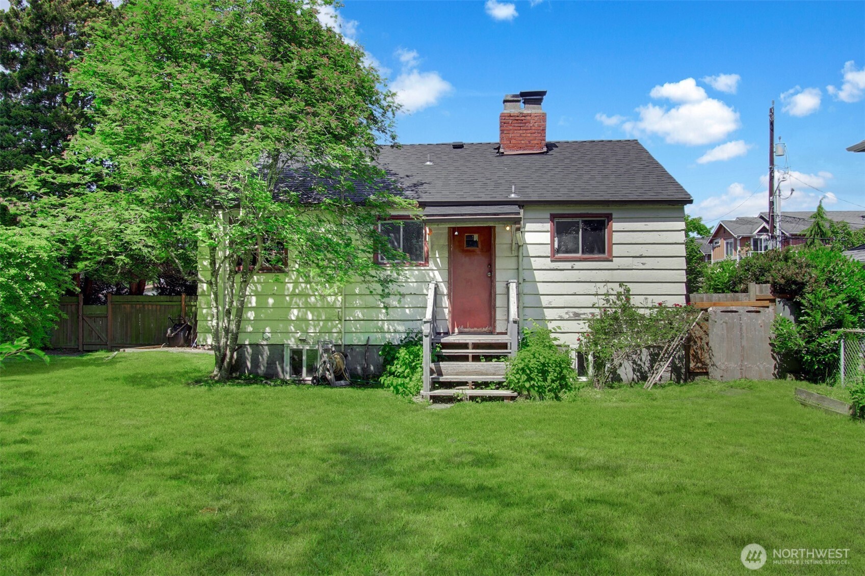 Back of the house. Charming backyard! Blooming hydrangeas and rhodedendrons! Raised flower beds. Big side yard with gate. Fully fenced. Very private and homey. Great for pets, play and entertaining!