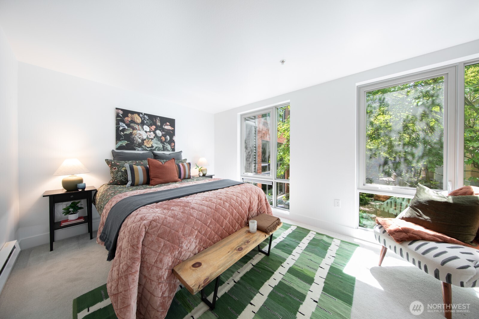 Peaceful primary bedroom with large windows and lush courtyard views.