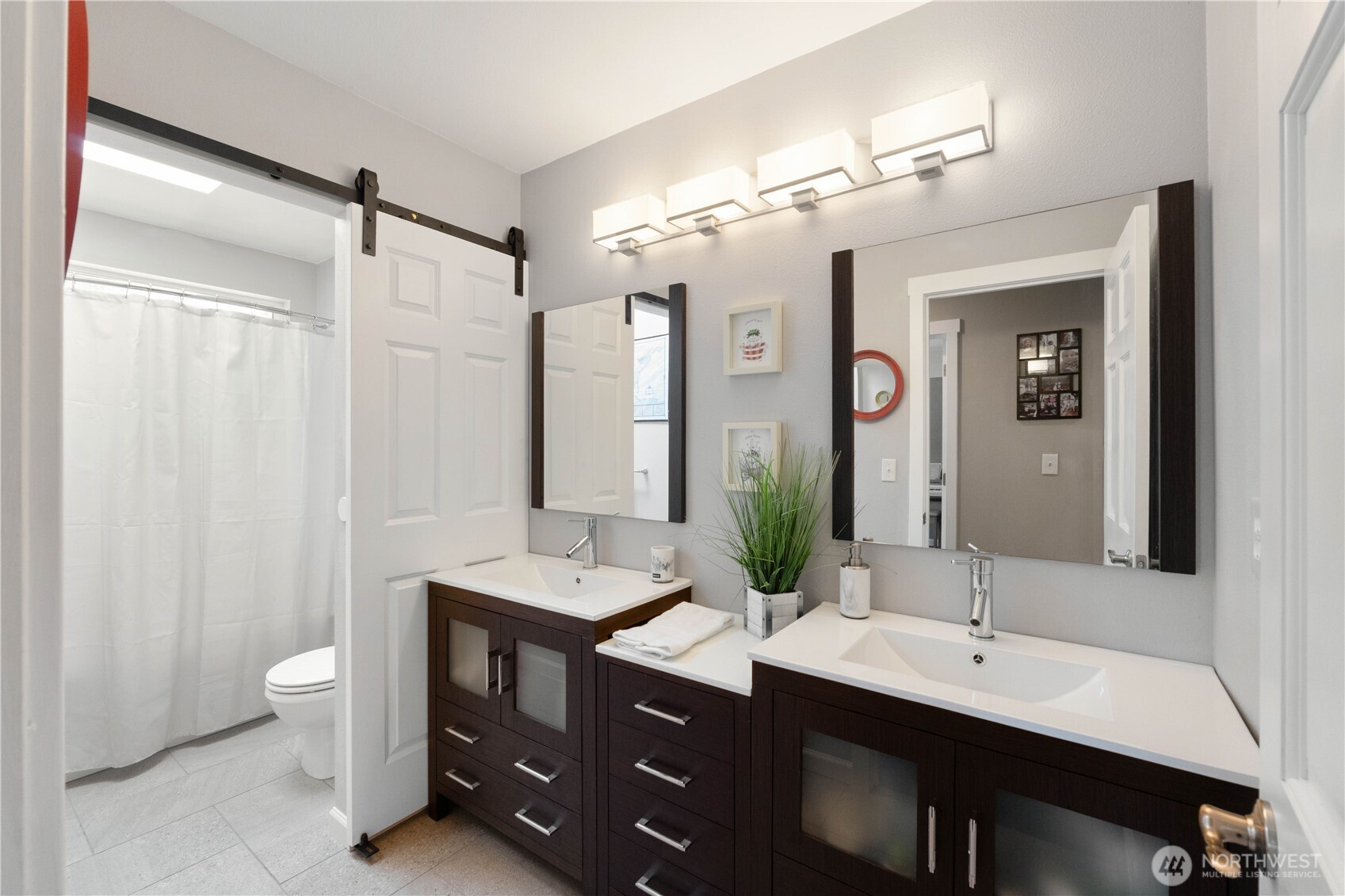 Large bathroom upstairs with double vanity, barndoor separating the tub/shower and toilet for privacy