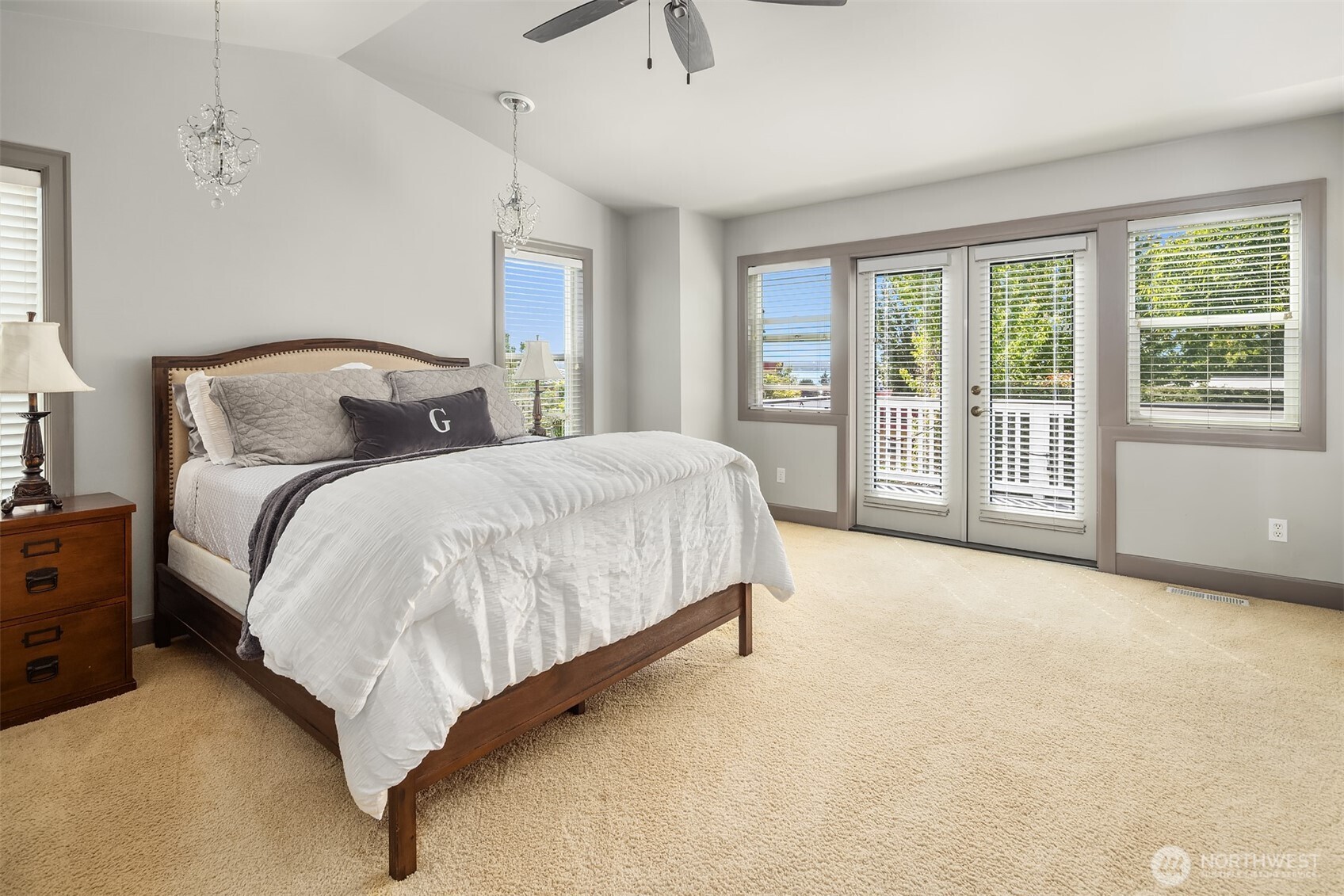Move upstairs to the wonderful primary suite! The pitched ceiling creates great character while ample windows and french doors provide lovely peak-a-boo views of beautiful Lake Washington and the Seattle skyline.