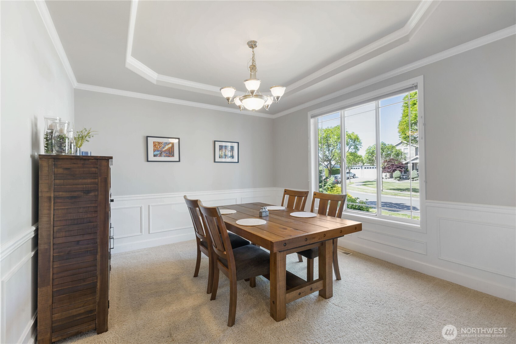 Elegant dining room with classic wainscoting and crisp white trim, enhanced by a large window that fills the space with natural light. A coved ceiling adds architectural charm, while convenient access to the butler’s pantry and kitchen makes entertaining a breeze.