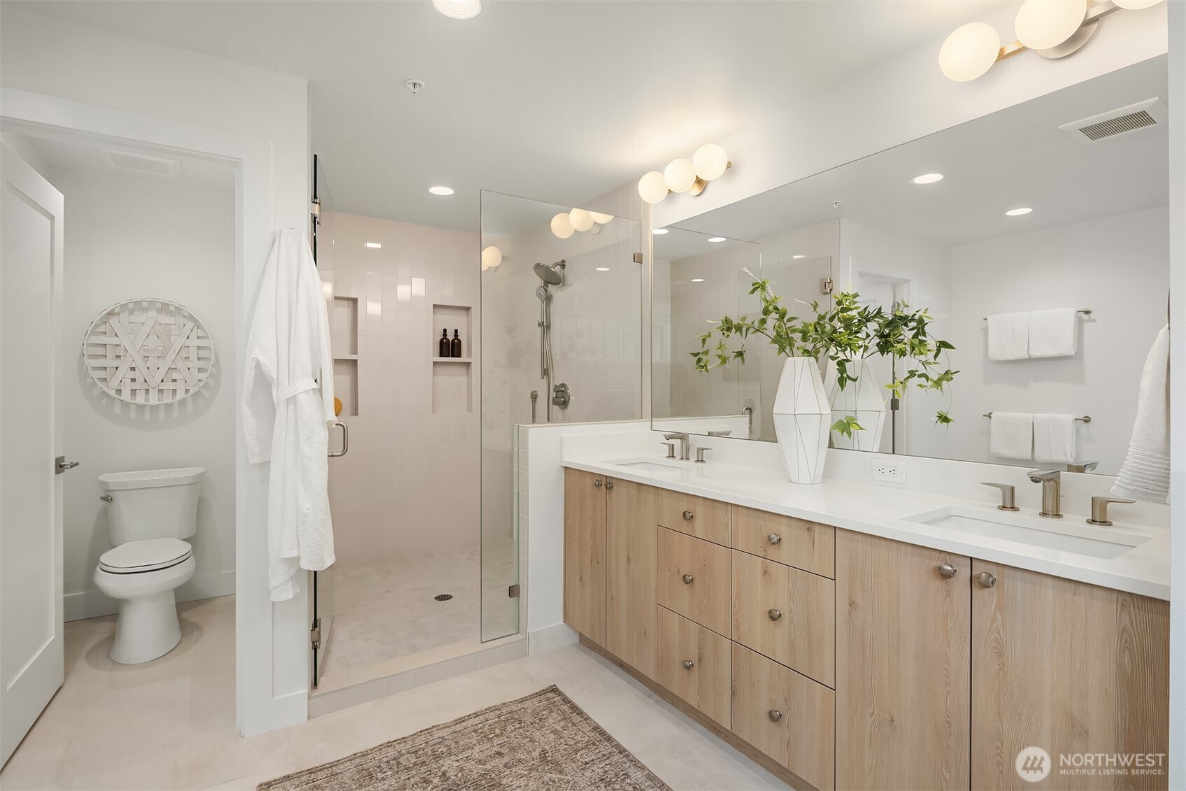 Primary en suite bathroom with dual vanities, water closet, standalone tub and large shower