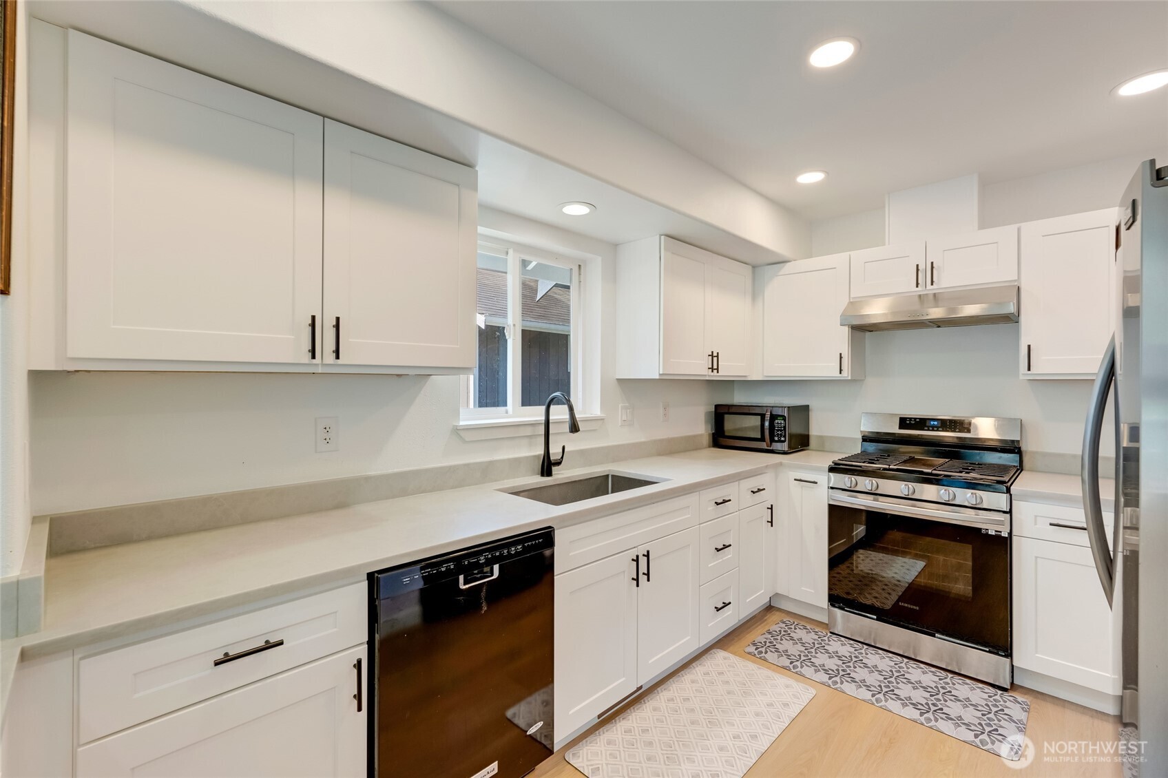 Modern kitchen w/ quartz counters, shaker cabinets & stainless steel appliances.