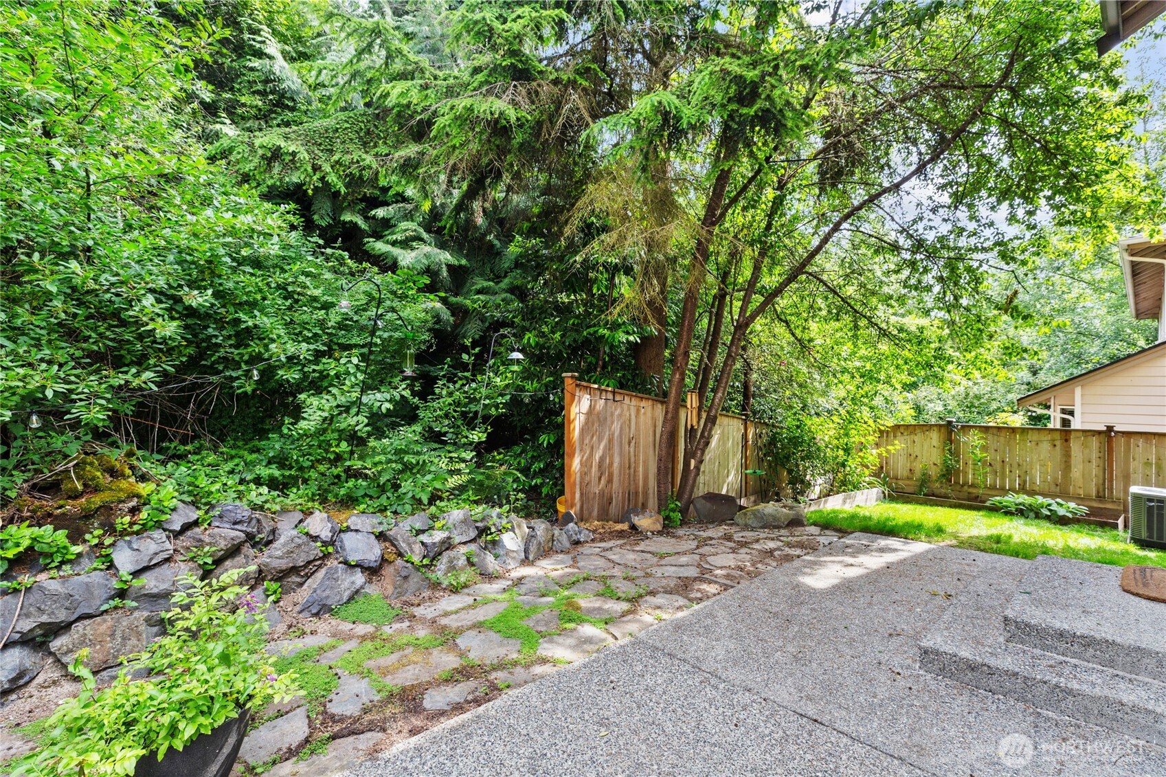 Peaceful backyard with a patio and stone pathway, backing to a lush, protected greenbelt that can never be developed- offering privacy and serene natural views year-round.