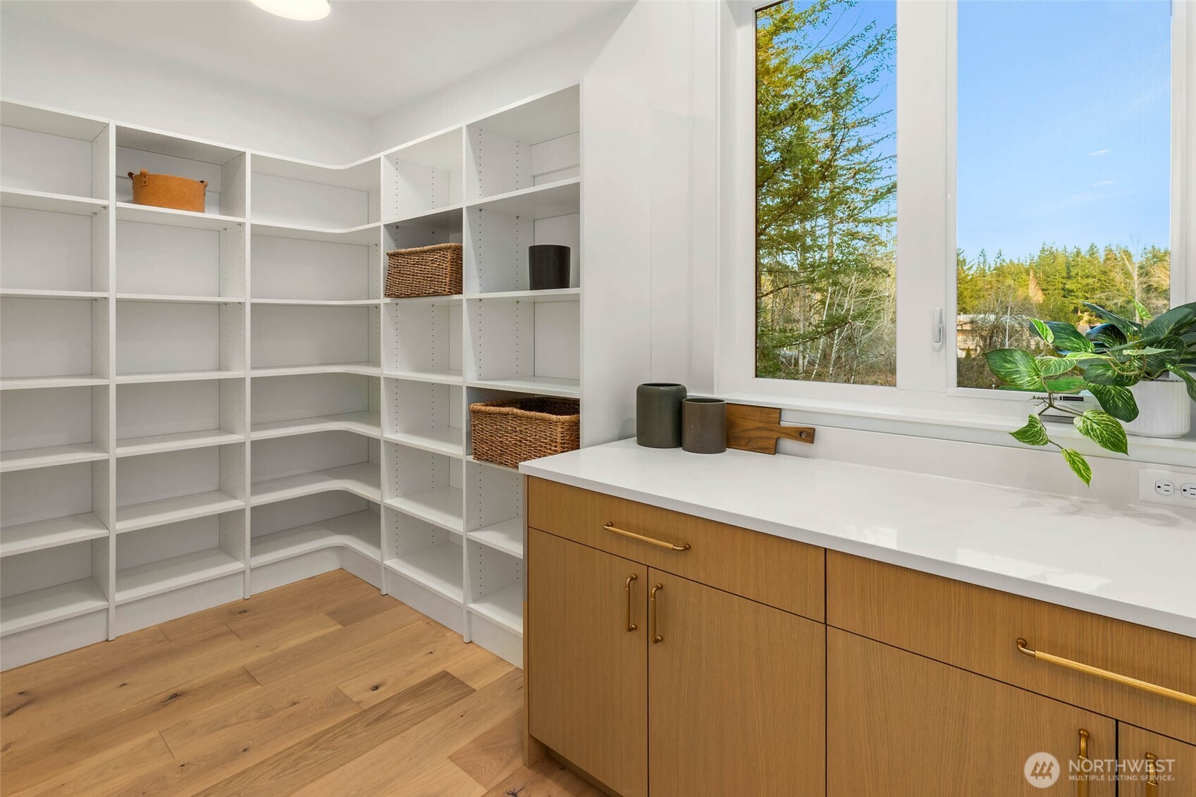 Expansive walk in pantry with solid shelving and custom cabinets with slab counters perfect for prep