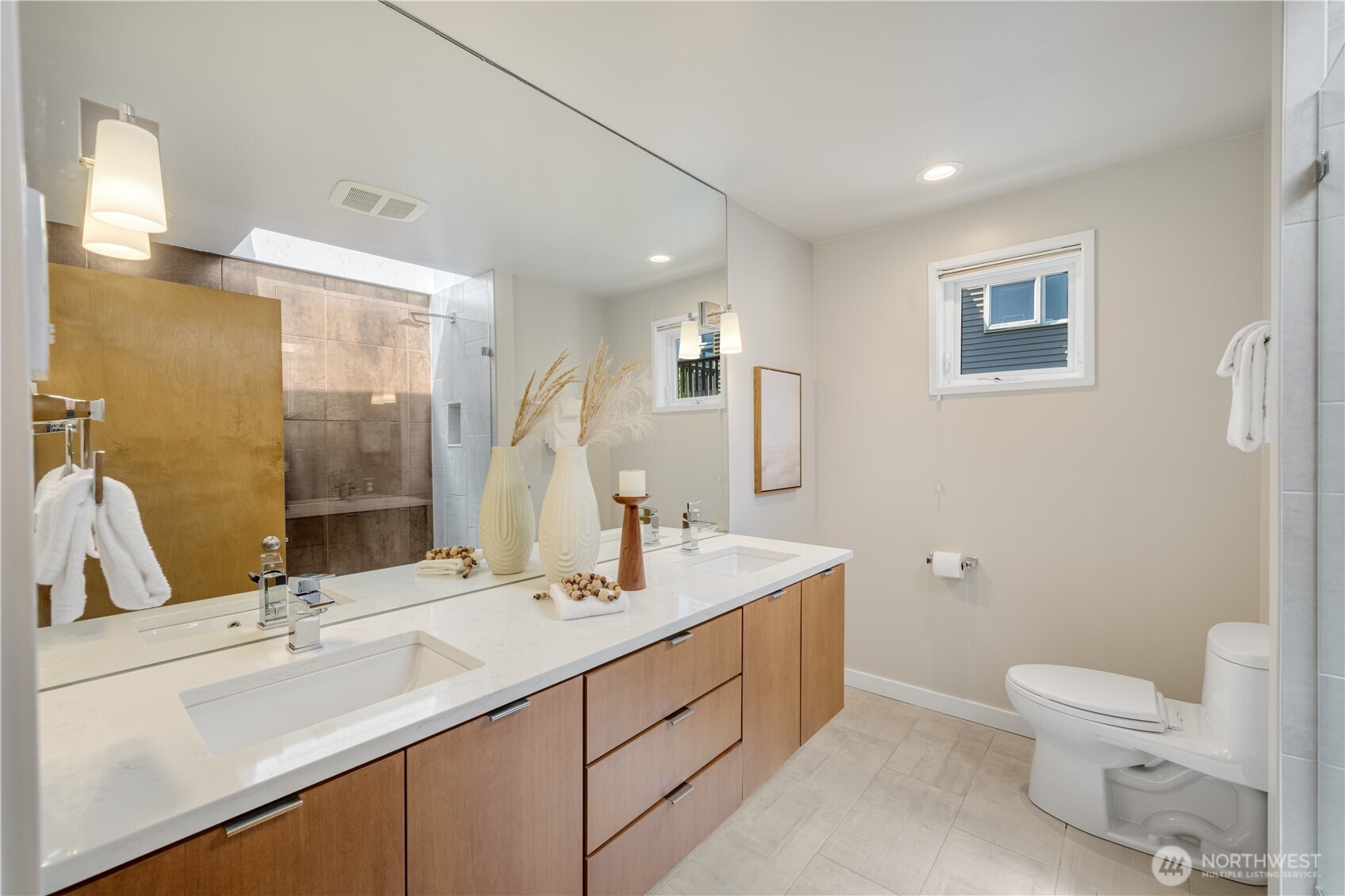 The remodeled hall bath features a floating vanity and skylit walk in shower
