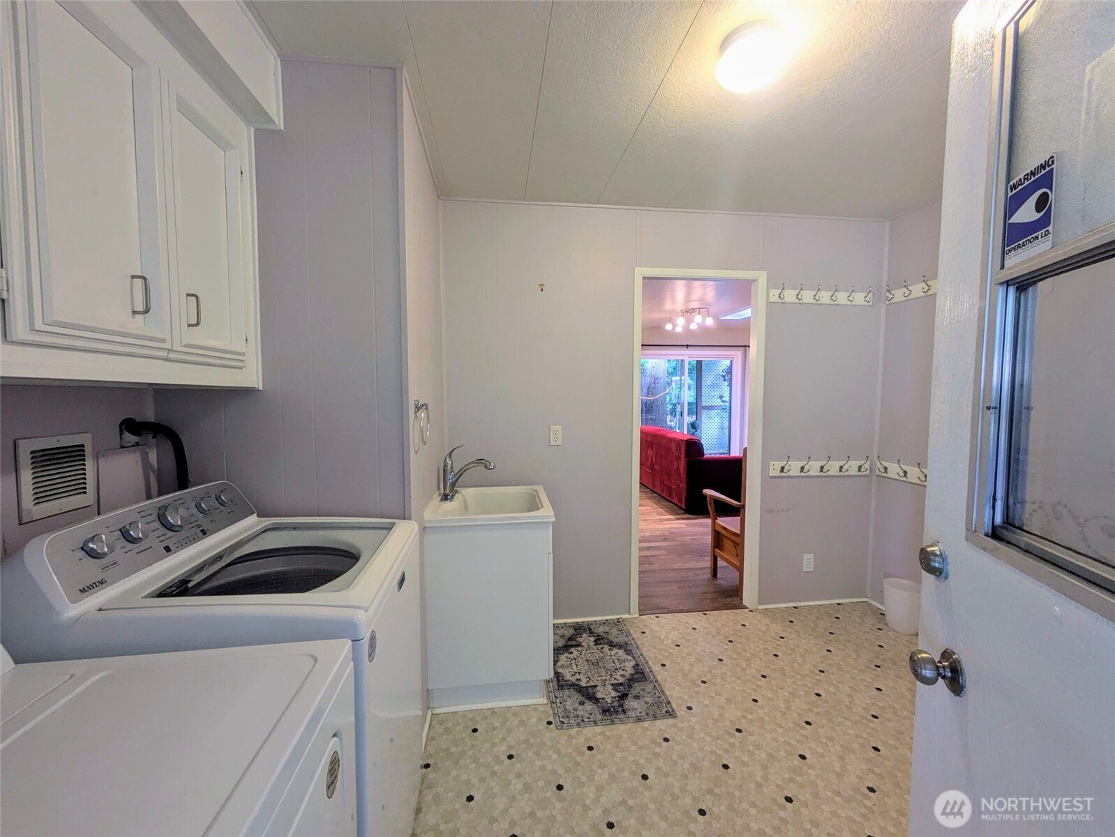 Laundry room door off the carport. This is a big laundry room with a utility sink and desk area. Wall hooks for coats, etc. Washer and dryer stay.