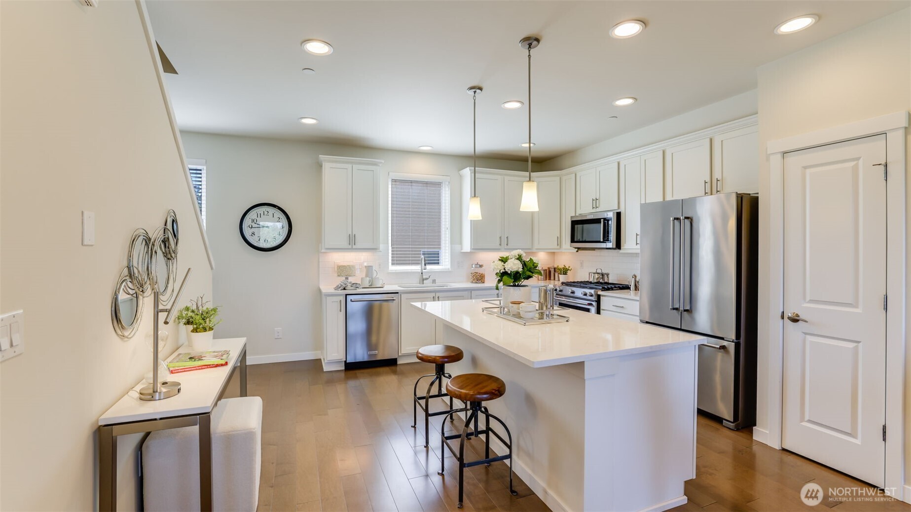The kitchen has been beautifully designed with hardwood floors, a large center island with eating bar and ample quartz counters, a pantry and just the right amount of modern lighting.