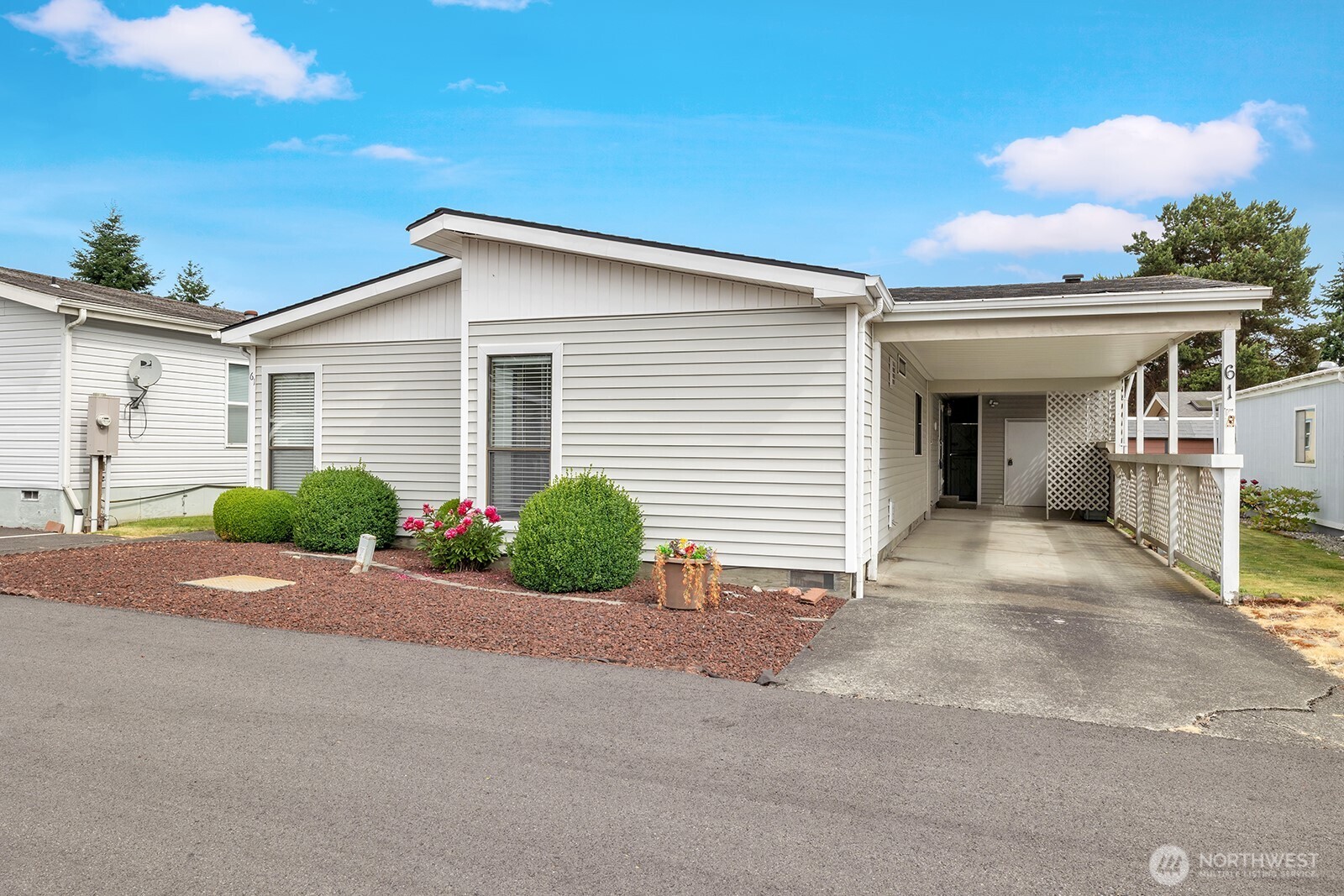 Street view of the home and the shows the deep carport, easy care landscaped yard. Mature shrubs and plants border the home and offer year-round color and greenery.