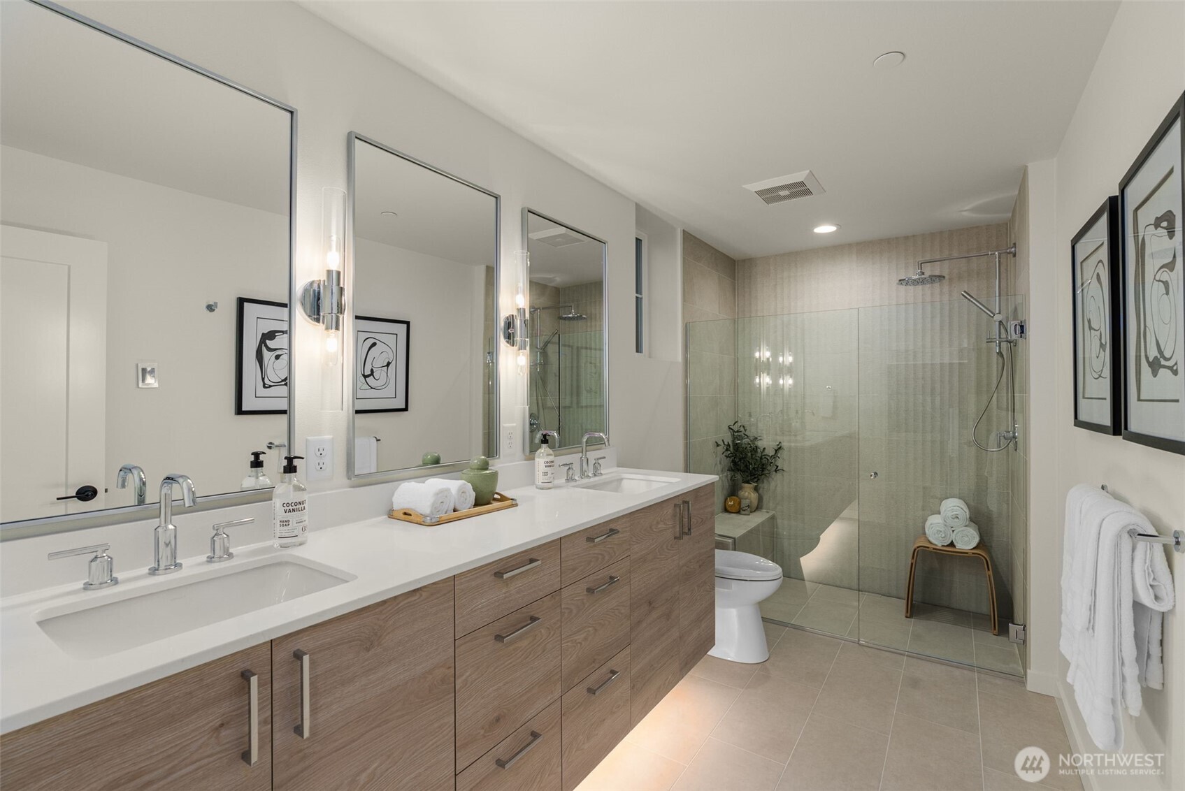 The primary bath is doing everything right—dual vanity, warm finishes, and a glass-enclosed rain shower ready for you!