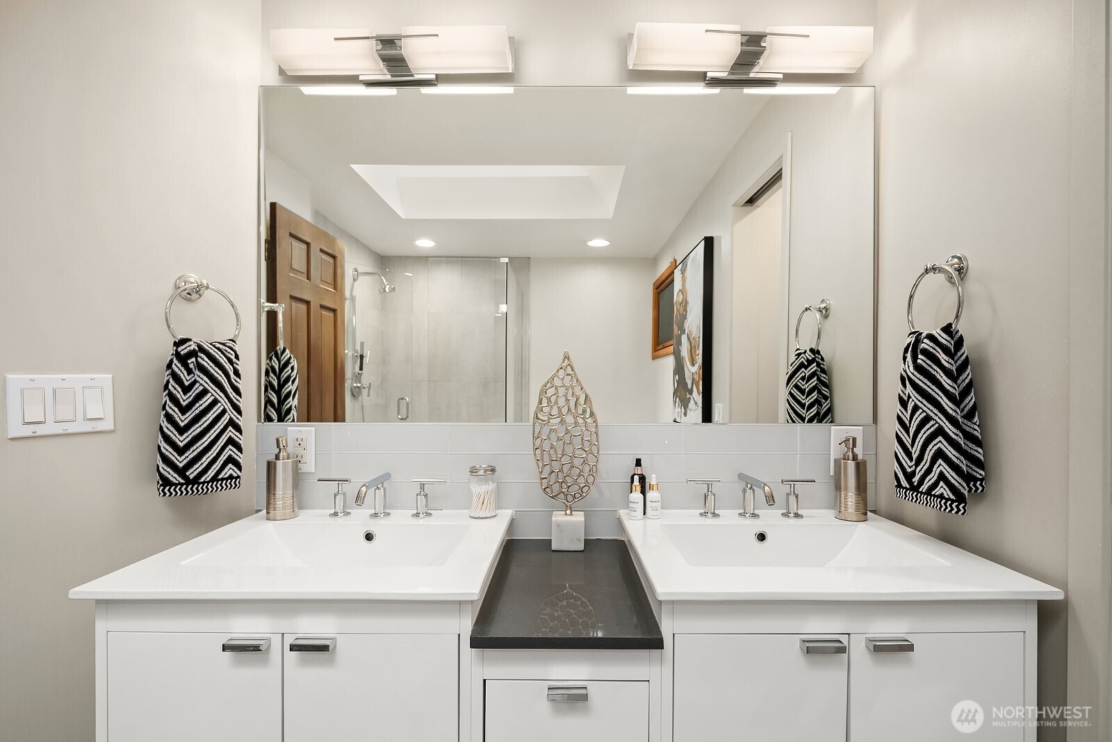 Primary bathroom with dual sink vanity, skylight, soaking tub and tile shower