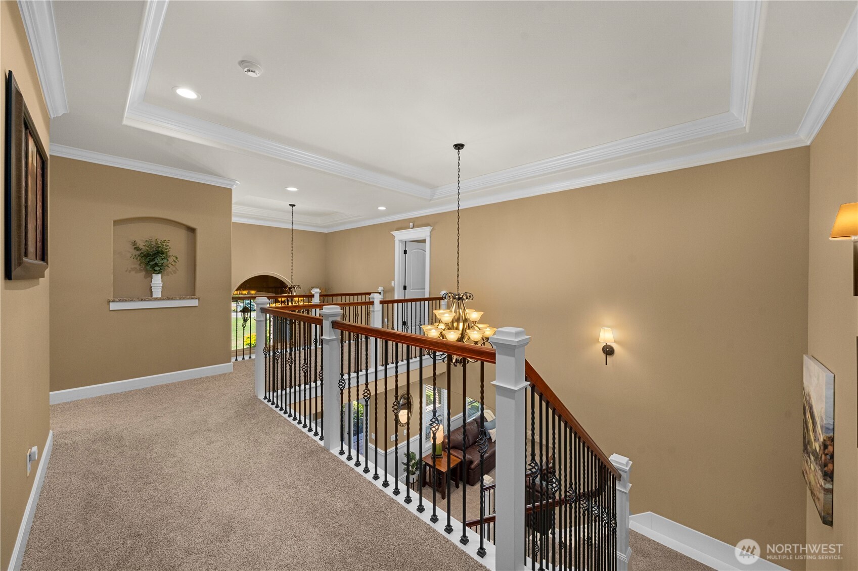 Landing shows continued double crown molding, wrought iron railing, art niche, open ceilings to lower level.