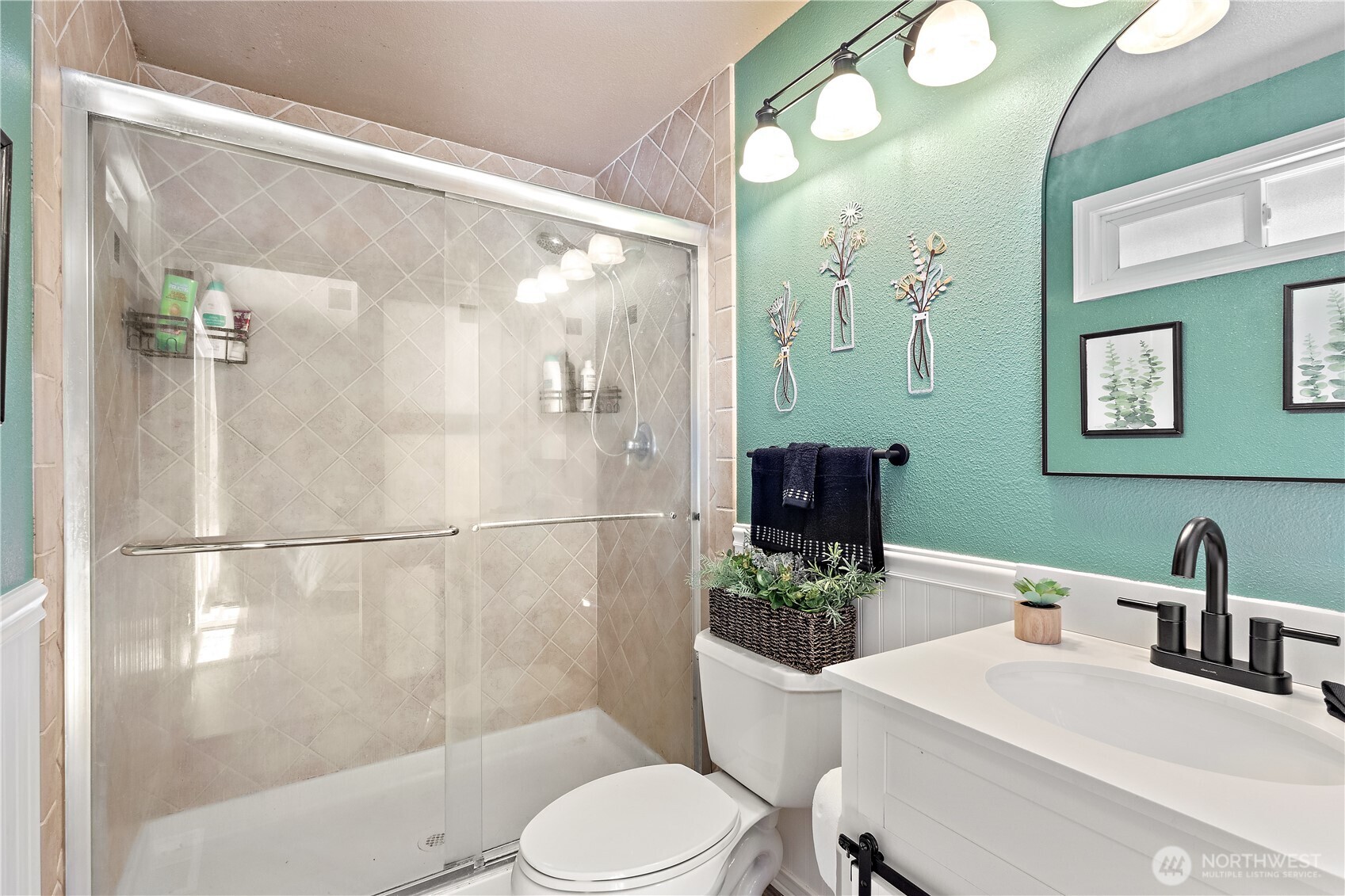 This refreshed en suite bathroom includes a tiled walk-in shower, upgraded vanity and mirror, new flooring, and charming barn door entry for added style.