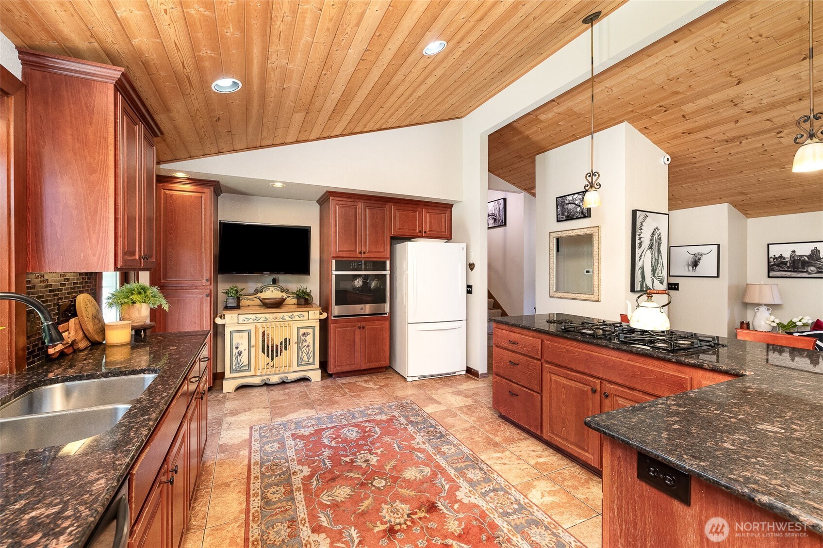 Ample counter space with granite counters and deep wood cabinets.