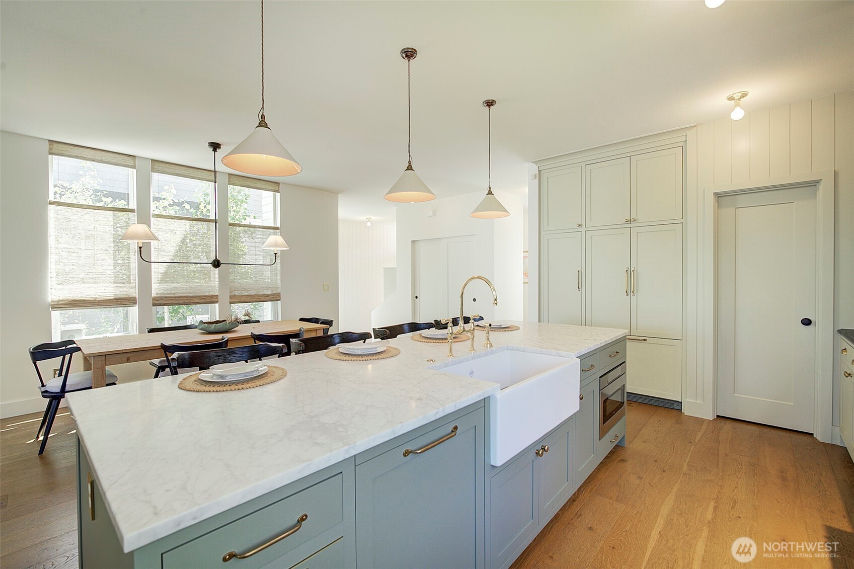 Luxury Chef's kitchen with Carrara marble island, soapstone countertops, pendant lights above island imported from England, custom handmade cabinetry with brass hardware, built-in coffee station, lime wash hood over imported ILVE range from Italy, custom-panel refrigerator from Fisher & Paykel, Rejuvenation light fixtures