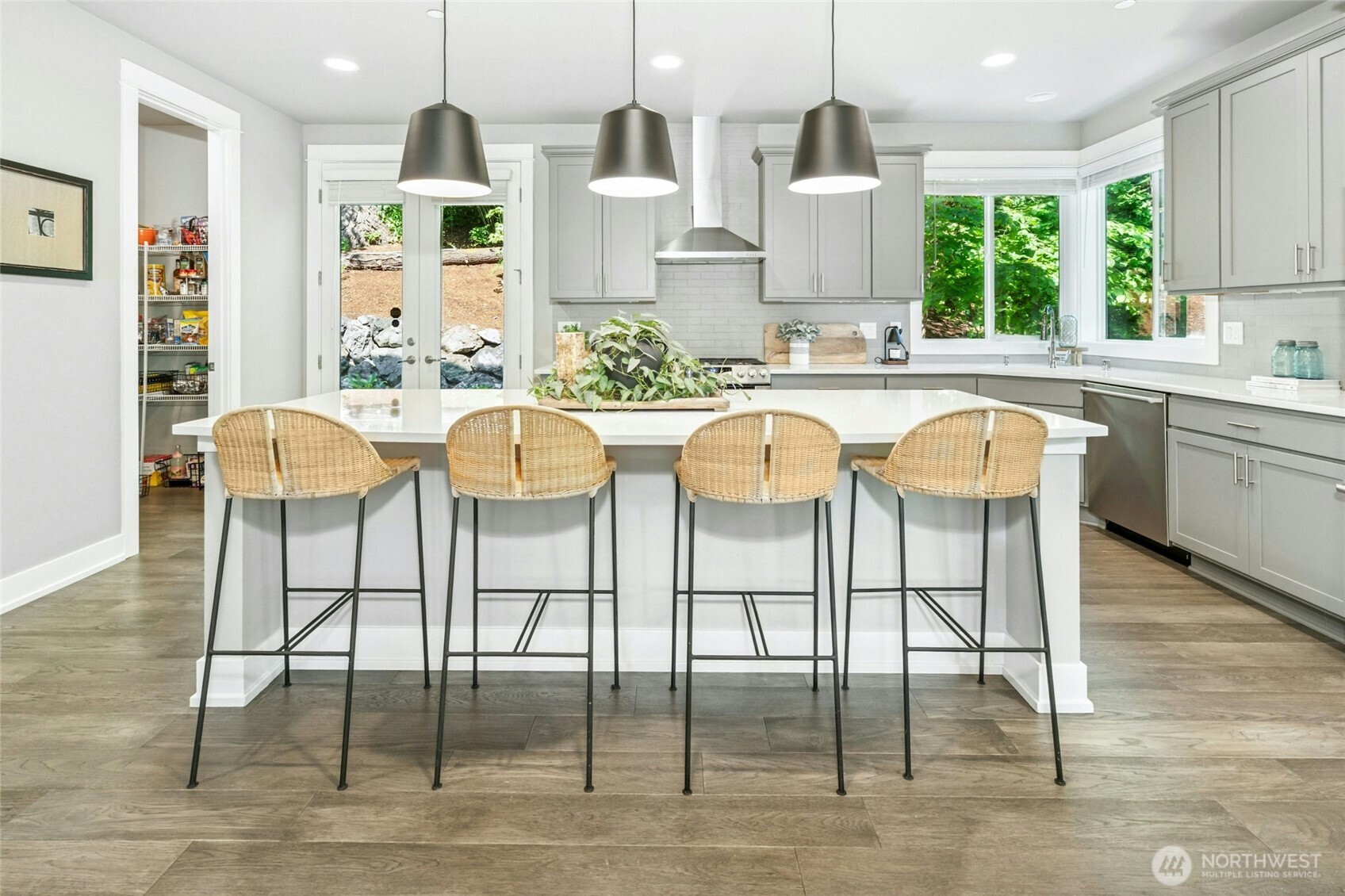 The large gourmet kitchen features quartz countertops, an oversized island with seating, stainless steel appliances, and a walk-in pantry for ample storage.