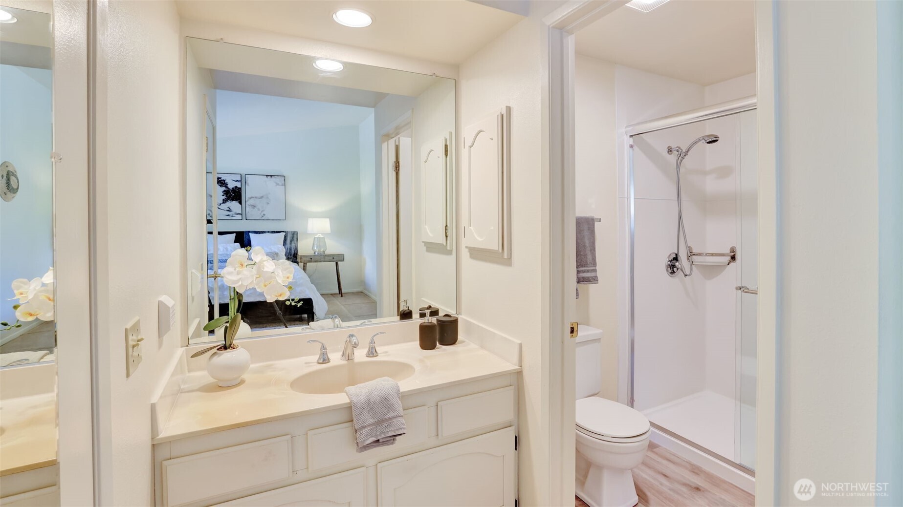 Nestled inside the primary bedroom, this ensuite bathroom features sleek countertops, abundant mirrors, and a separate toilet and walk-in shower, combining style and functionality