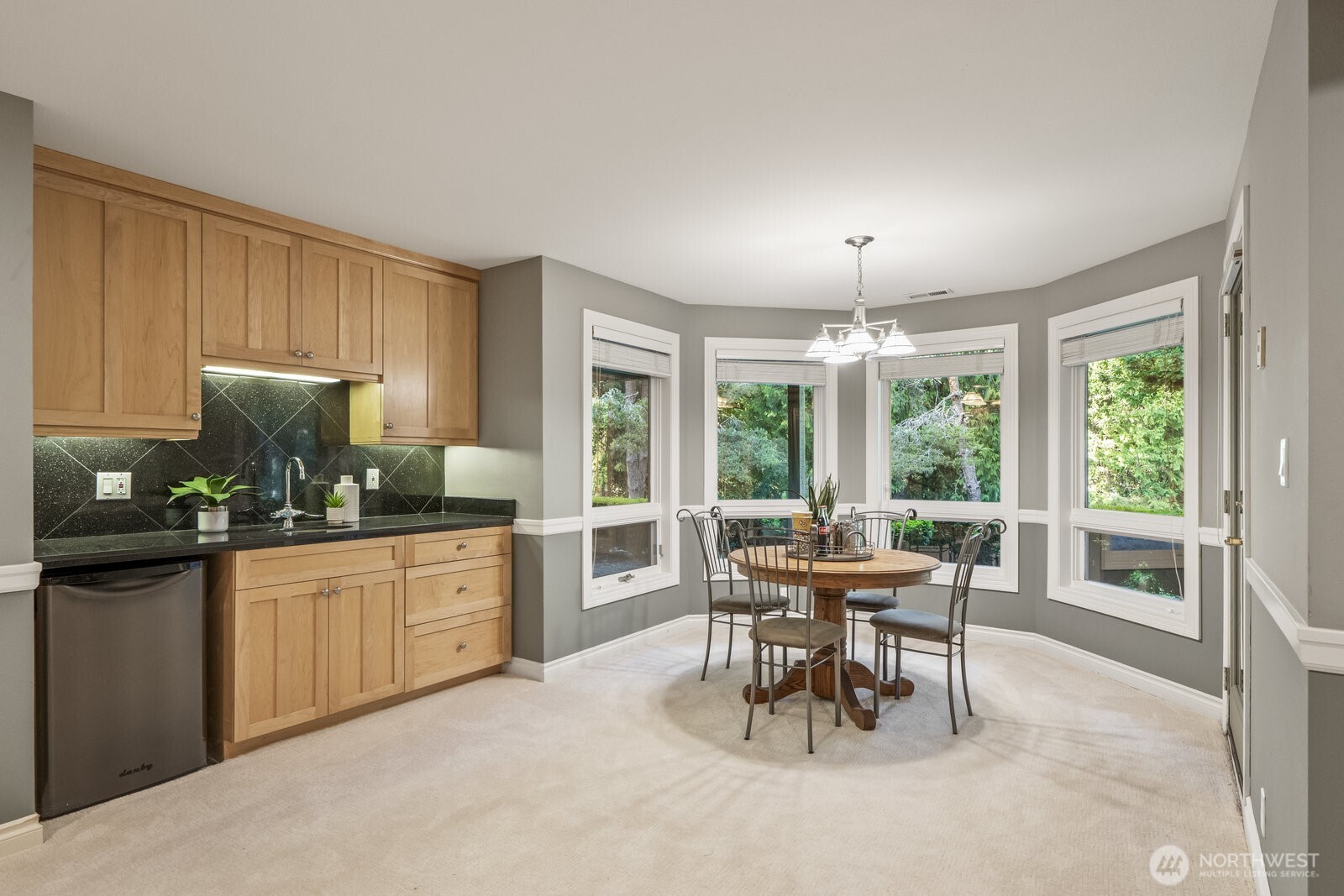 A slab granite beverage center with sink and refrigerator, temperature controlled 700 bottle wine room and door leading to the patio and backyard.