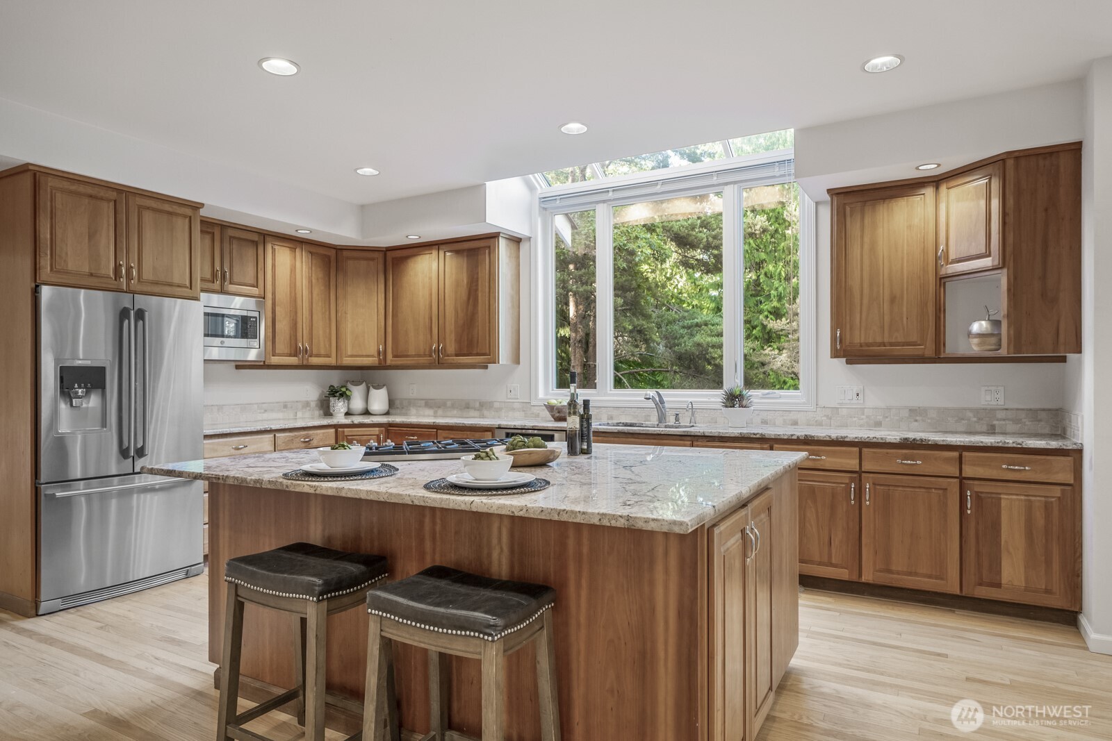 Cherry cabinetry with a natural finish, slab granite counters and tumbled marble back splash.