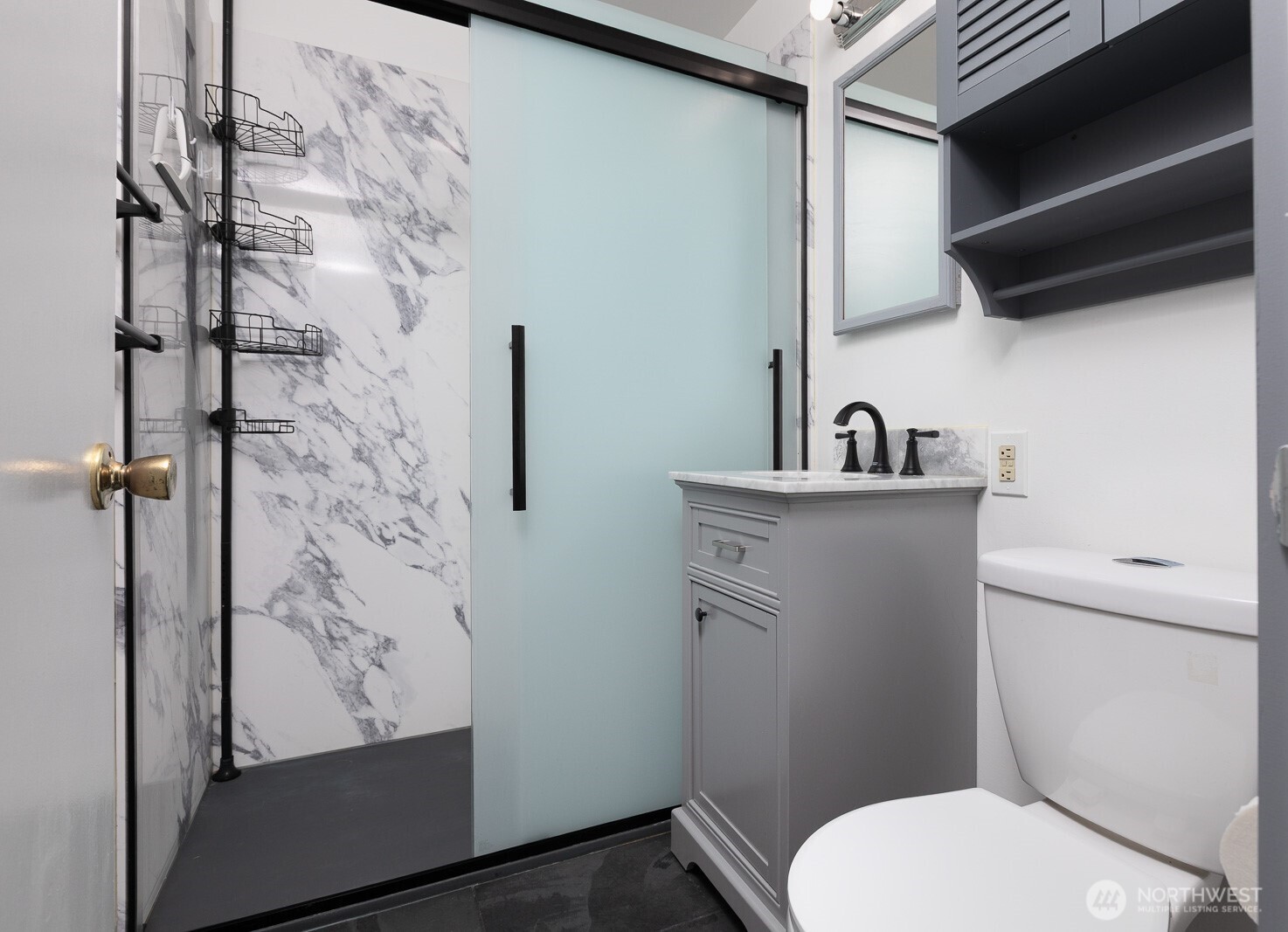 Updated bath is perfect for someone who has trouble lifting a foot. It's really pretty with it's marble style paneling and I love the dark fixtures!