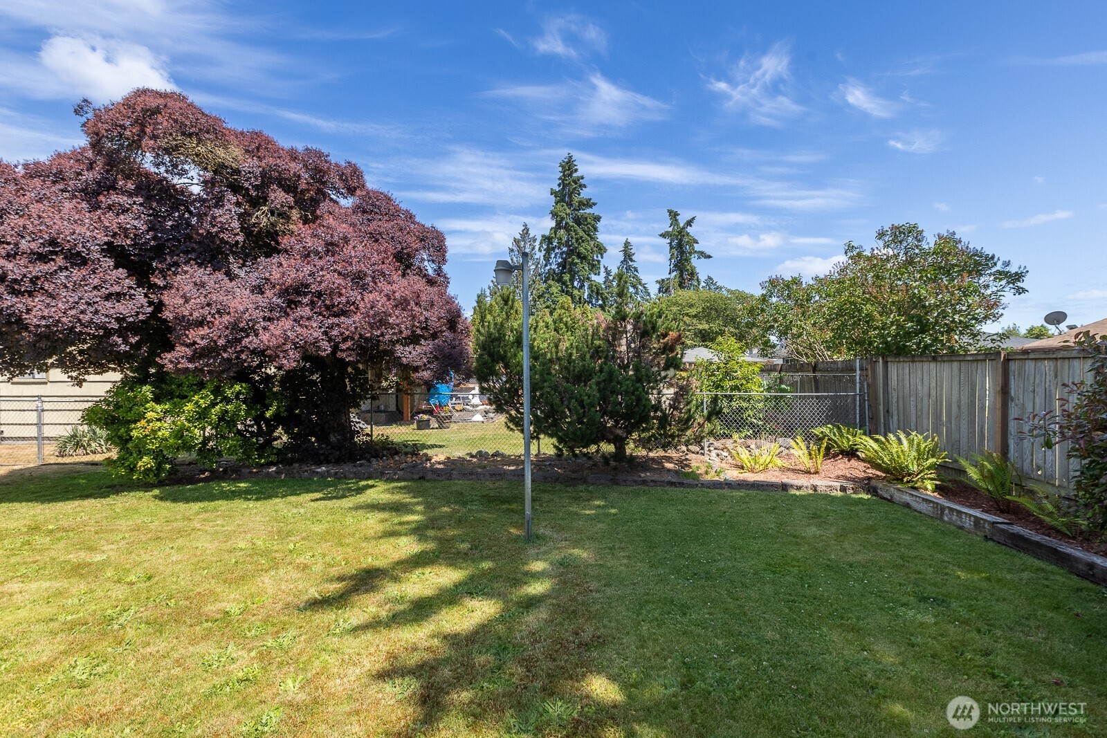 Pretty back yard with flagpole and pretty trees.